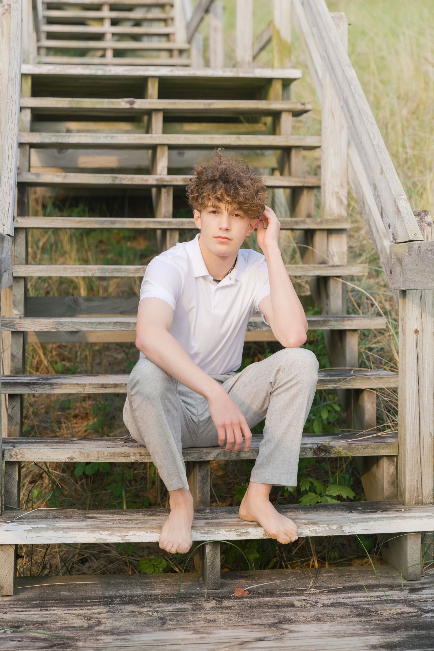 Grand Haven Lake Michigan Beach Senior Portrait Photoshoot. Sand dunes, beach grass, and the great lakes on the boardwalk with a surfboard