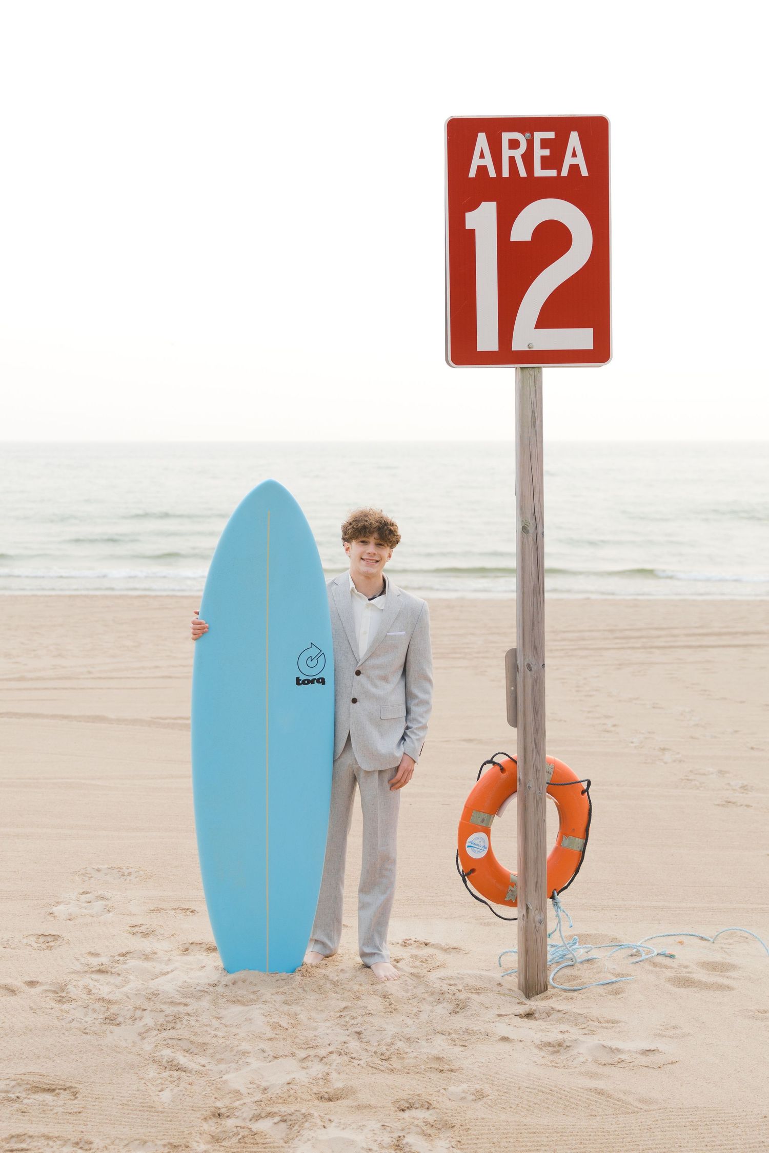 Grand Haven Lake Michigan Beach Senior Portrait Photoshoot. Sand dunes, beach grass, and the great lakes on the boardwalk with a surfboard