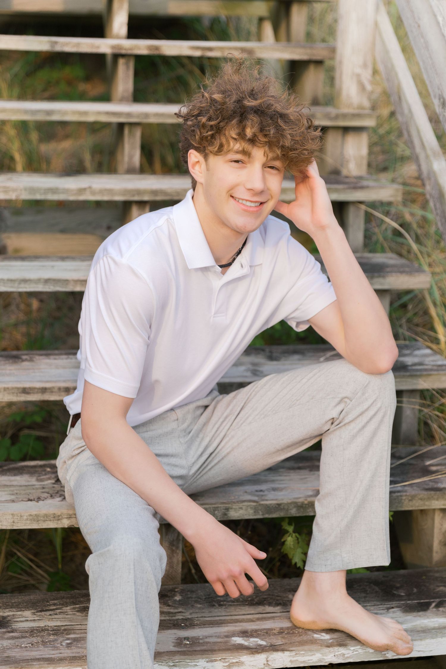 Grand Haven Lake Michigan Beach Senior Portrait Photoshoot. Sand dunes, beach grass, and the great lakes on the boardwalk with a surfboard