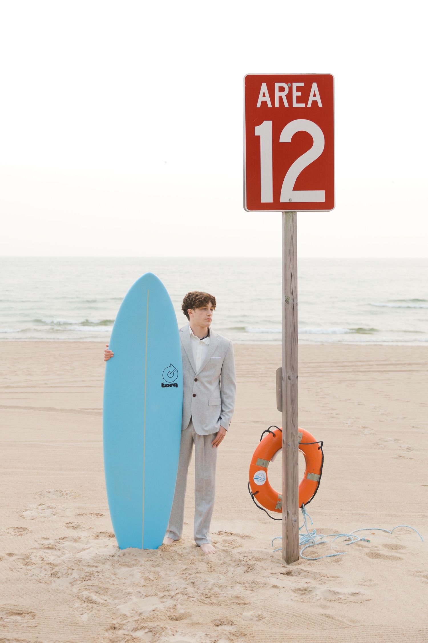 Grand Haven Lake Michigan Beach Senior Portrait Photoshoot. Sand dunes, beach grass, and the great lakes on the boardwalk with a surfboard