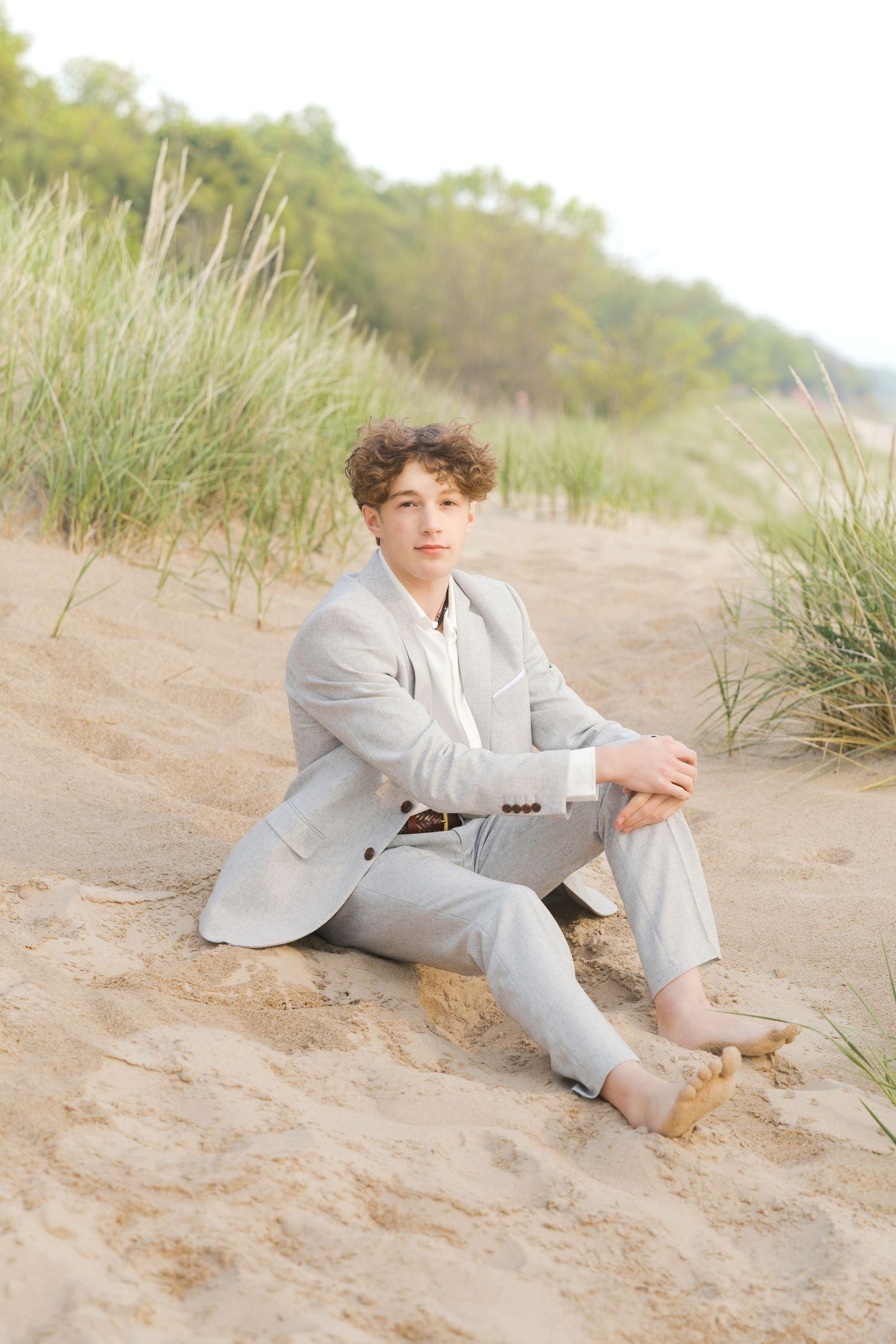 Grand Haven Lake Michigan Beach Senior Portrait Photoshoot. Sand dunes, beach grass, and the great lakes on the boardwalk with a surfboard