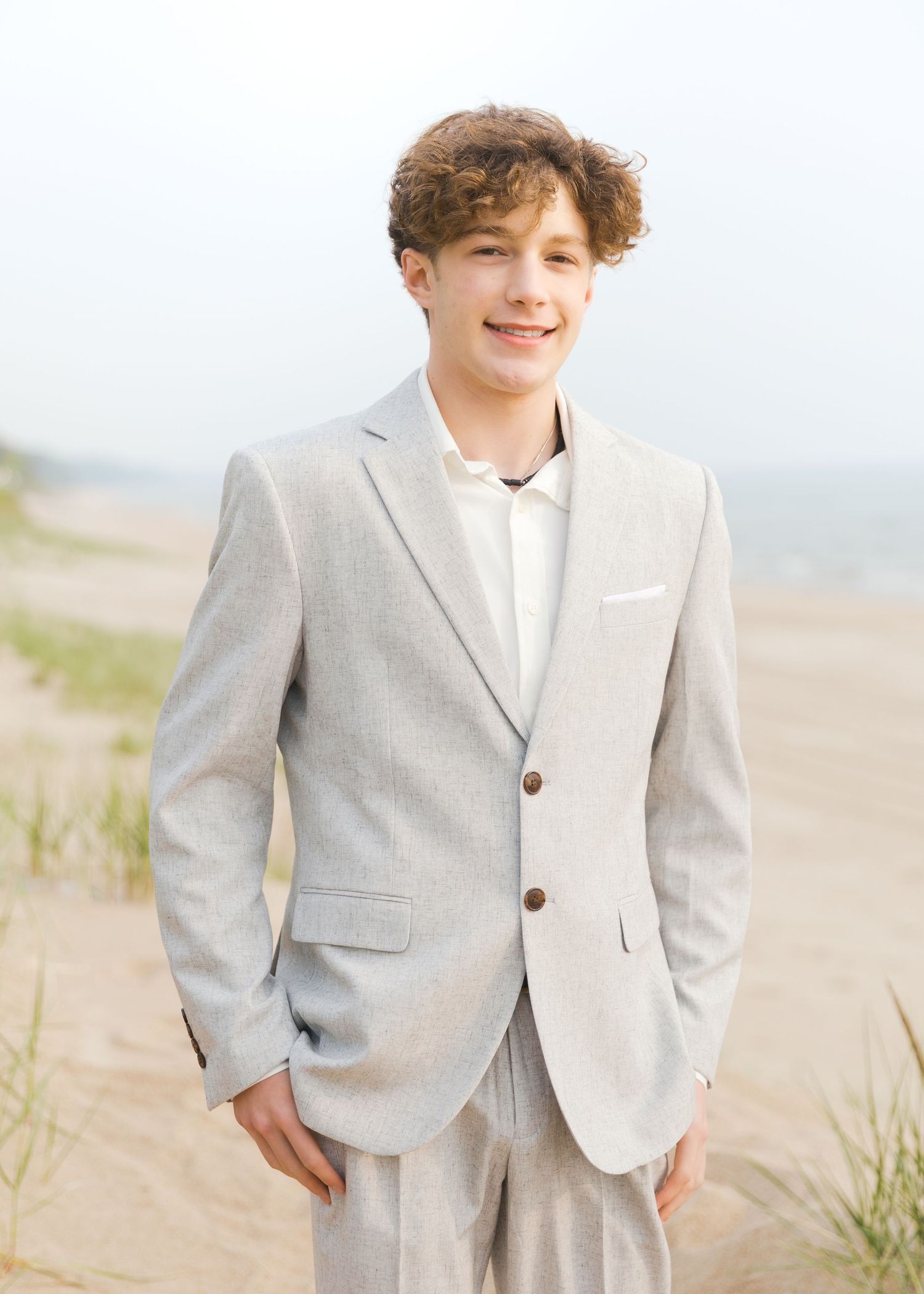 Grand Haven Lake Michigan Beach Senior Portrait Photoshoot. Sand dunes, beach grass, and the great lakes on the boardwalk with a surfboard