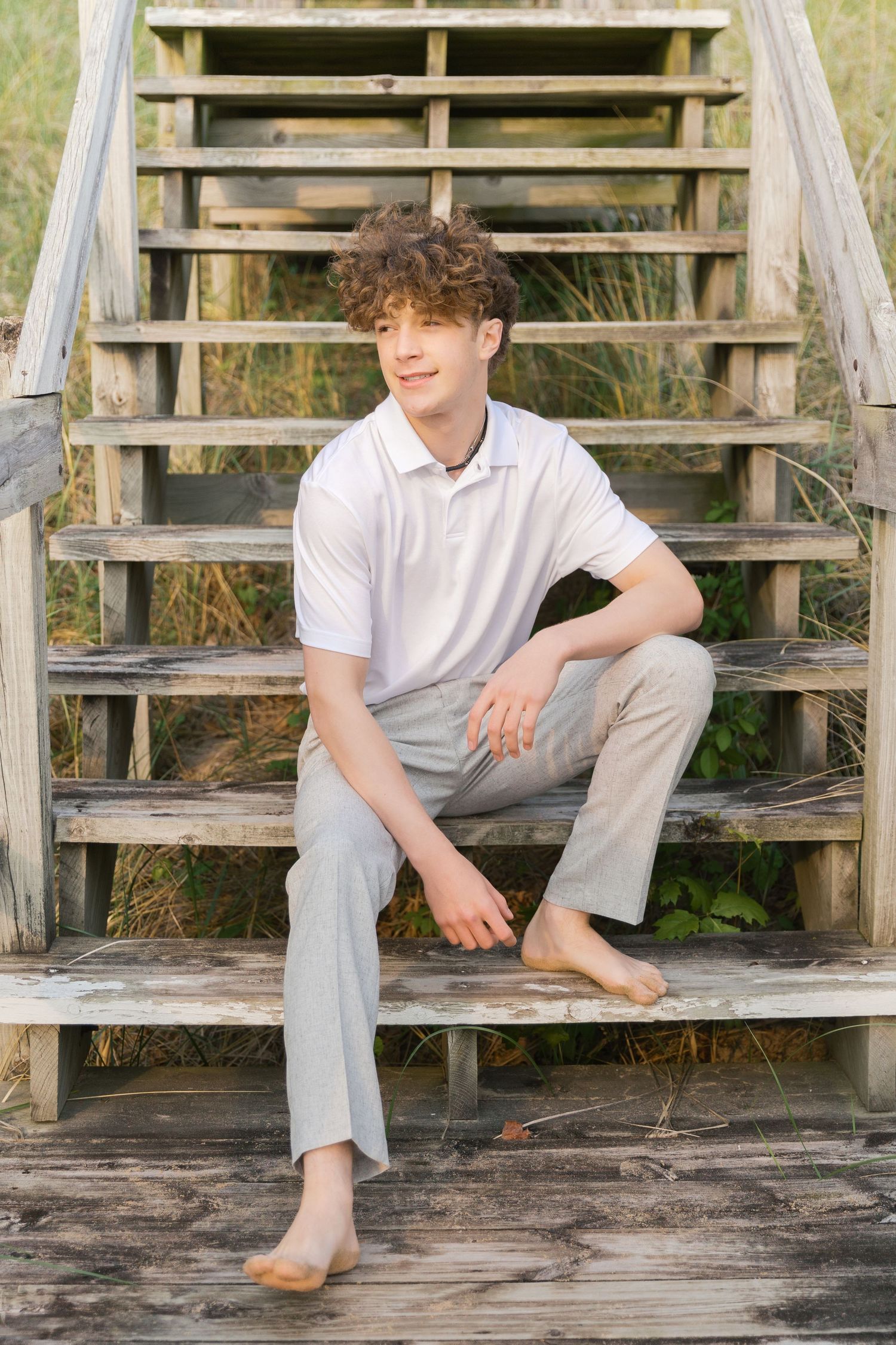 Grand Haven Lake Michigan Beach Senior Portrait Photoshoot. Sand dunes, beach grass, and the great lakes on the boardwalk with a surfboard