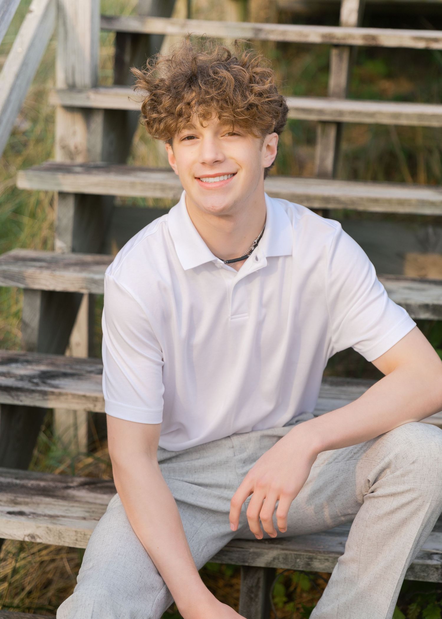 Grand Haven Lake Michigan Beach Senior Portrait Photoshoot. Sand dunes, beach grass, and the great lakes on the boardwalk with a surfboard
