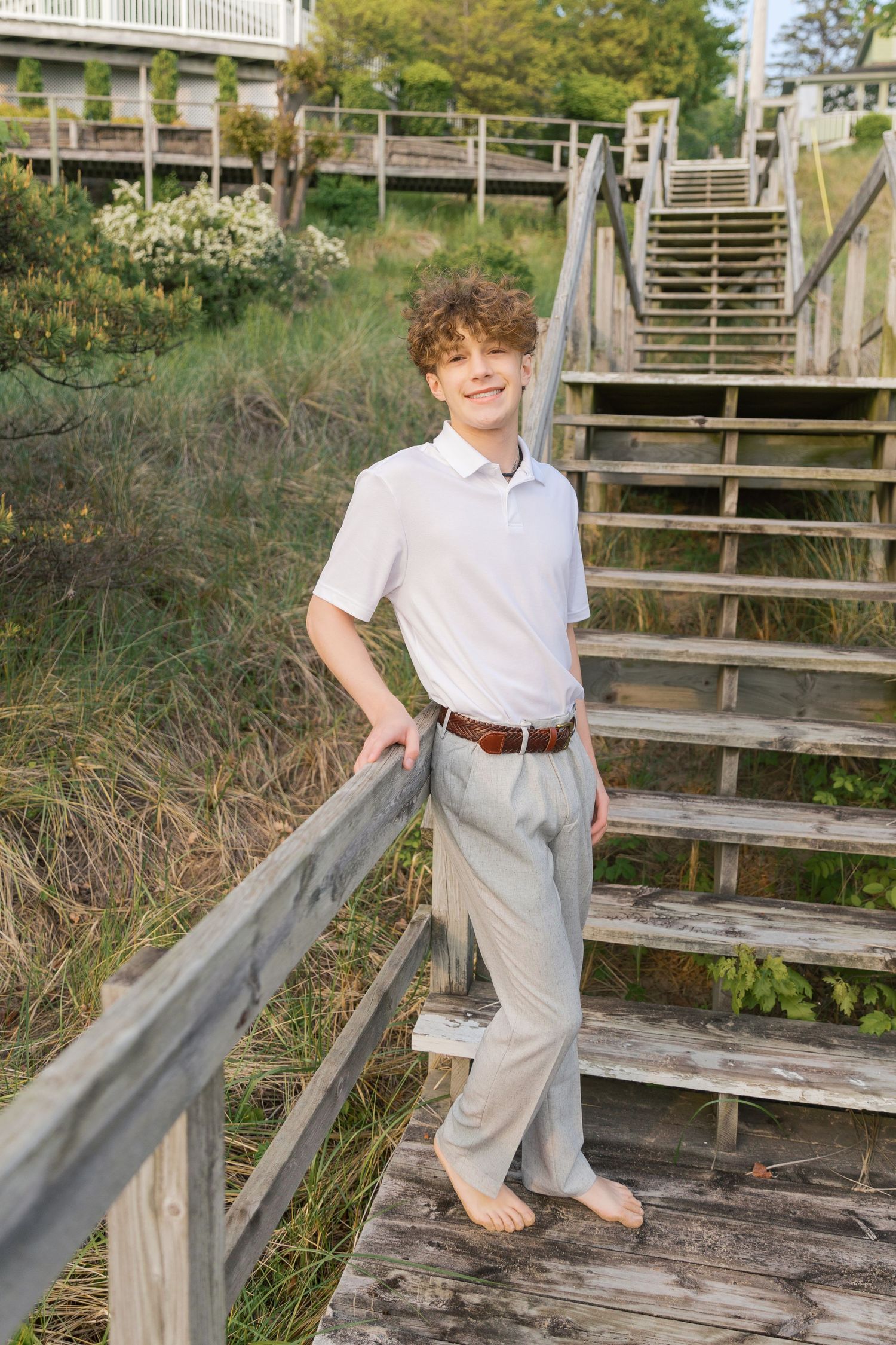 Grand Haven Lake Michigan Beach Senior Portrait Photoshoot. Sand dunes, beach grass, and the great lakes on the boardwalk with a surfboard