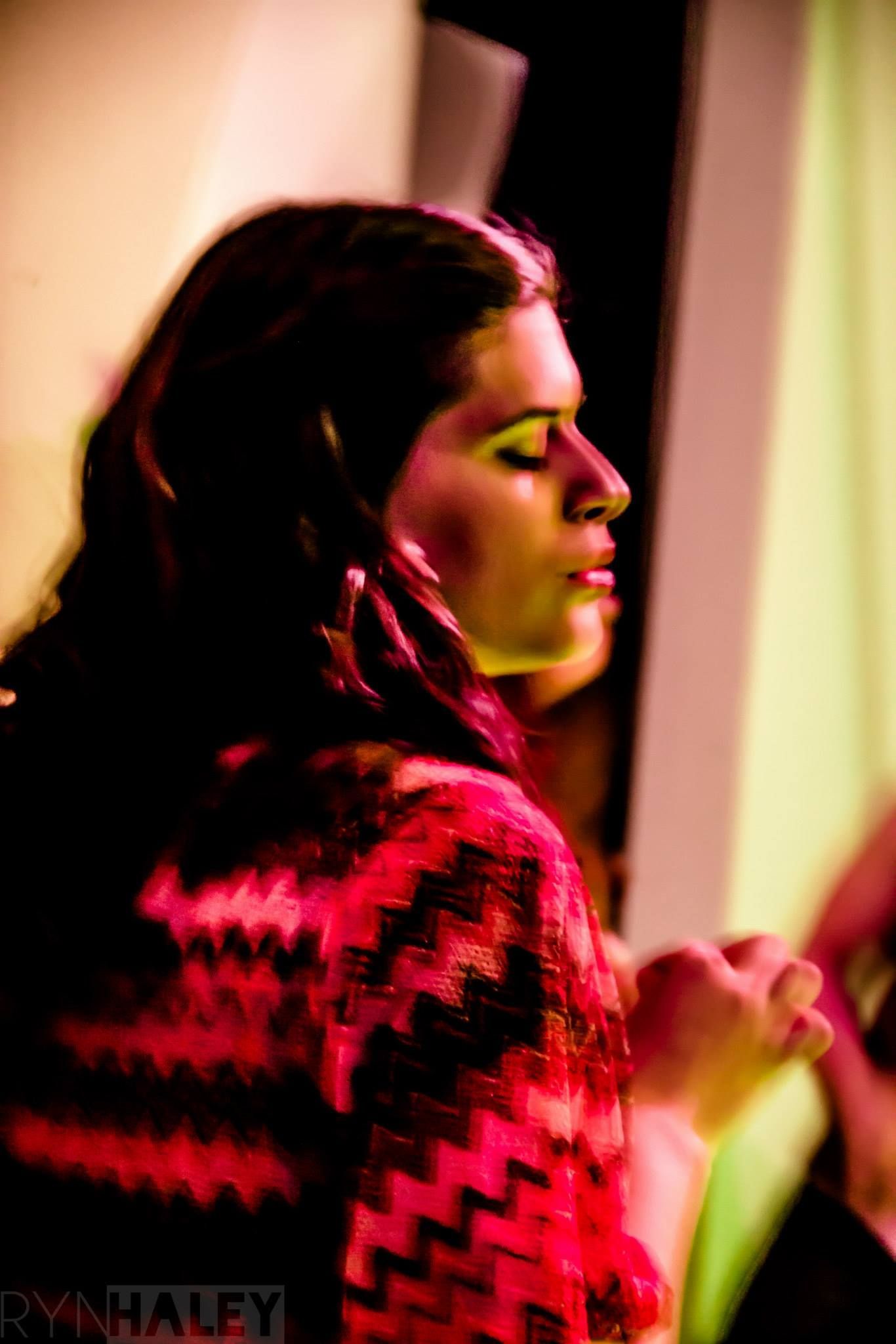 A silhouette in profile view illuminated by dramatic red lighting against a light background.