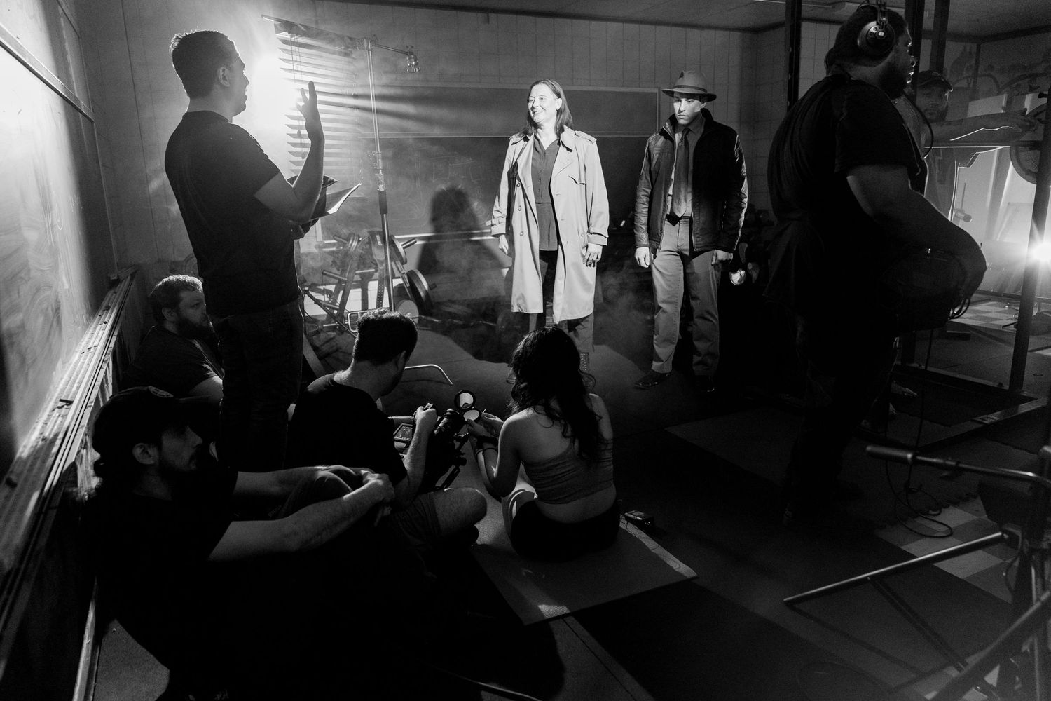 Behind-the-scenes silhouettes of film production crew working in a dark space.