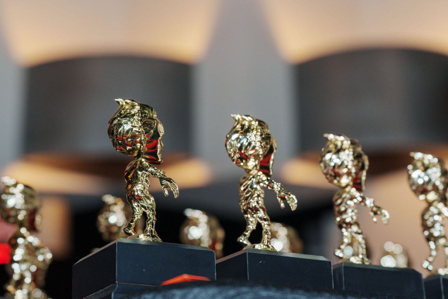 Row of golden trophy awards displayed on a shelf with decorative details.
