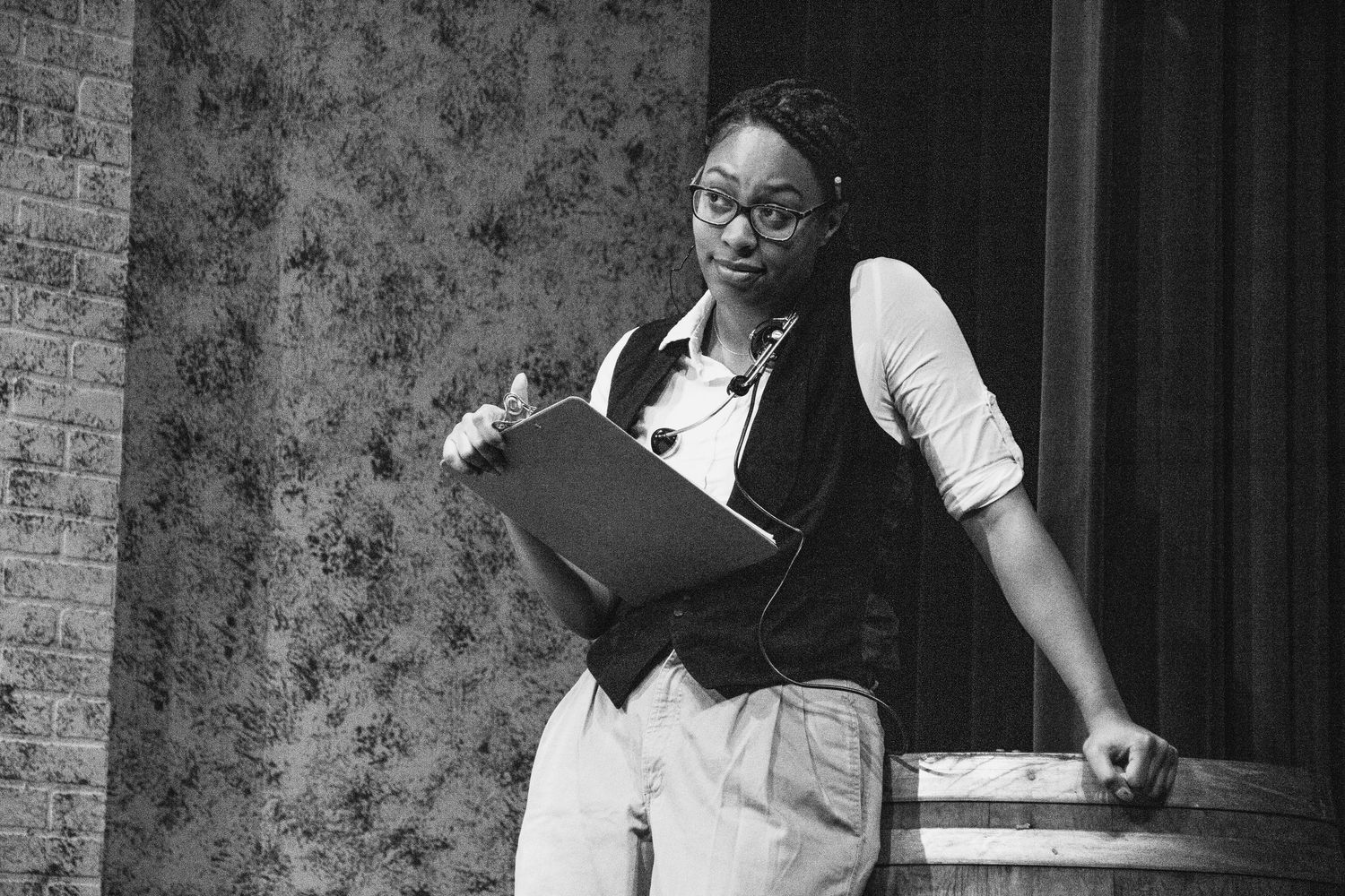 Black and white theatrical performance with dramatic lighting and expressive gestures on stage.