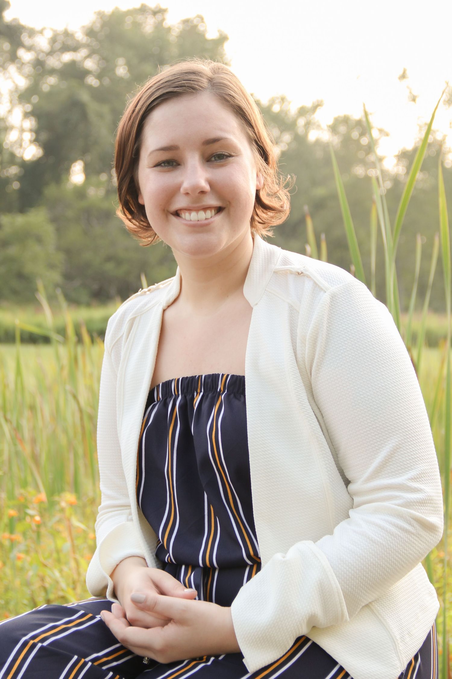 Outdoor summer portrait wearing striped dress and white cardigan.