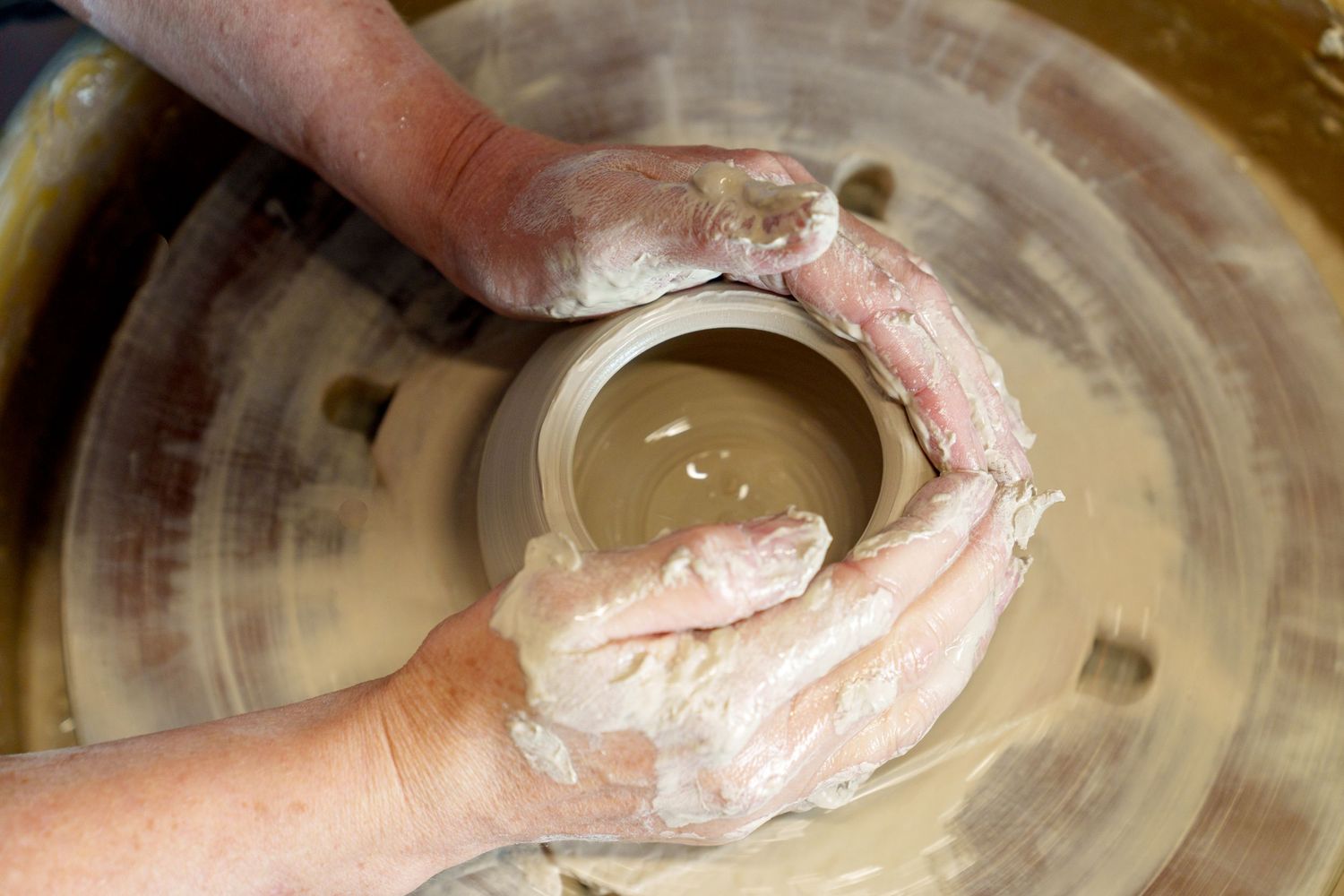 Hands kneading dough on a floured surface showing baking technique.