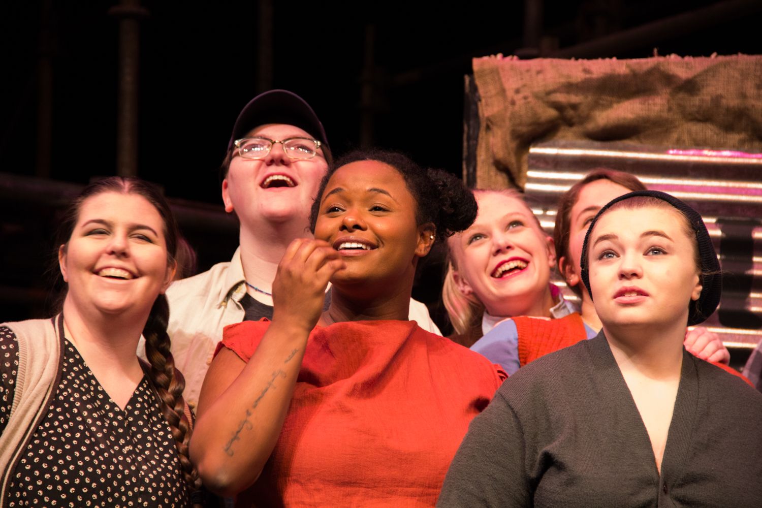 Theater audience members laughing and enjoying a performance.