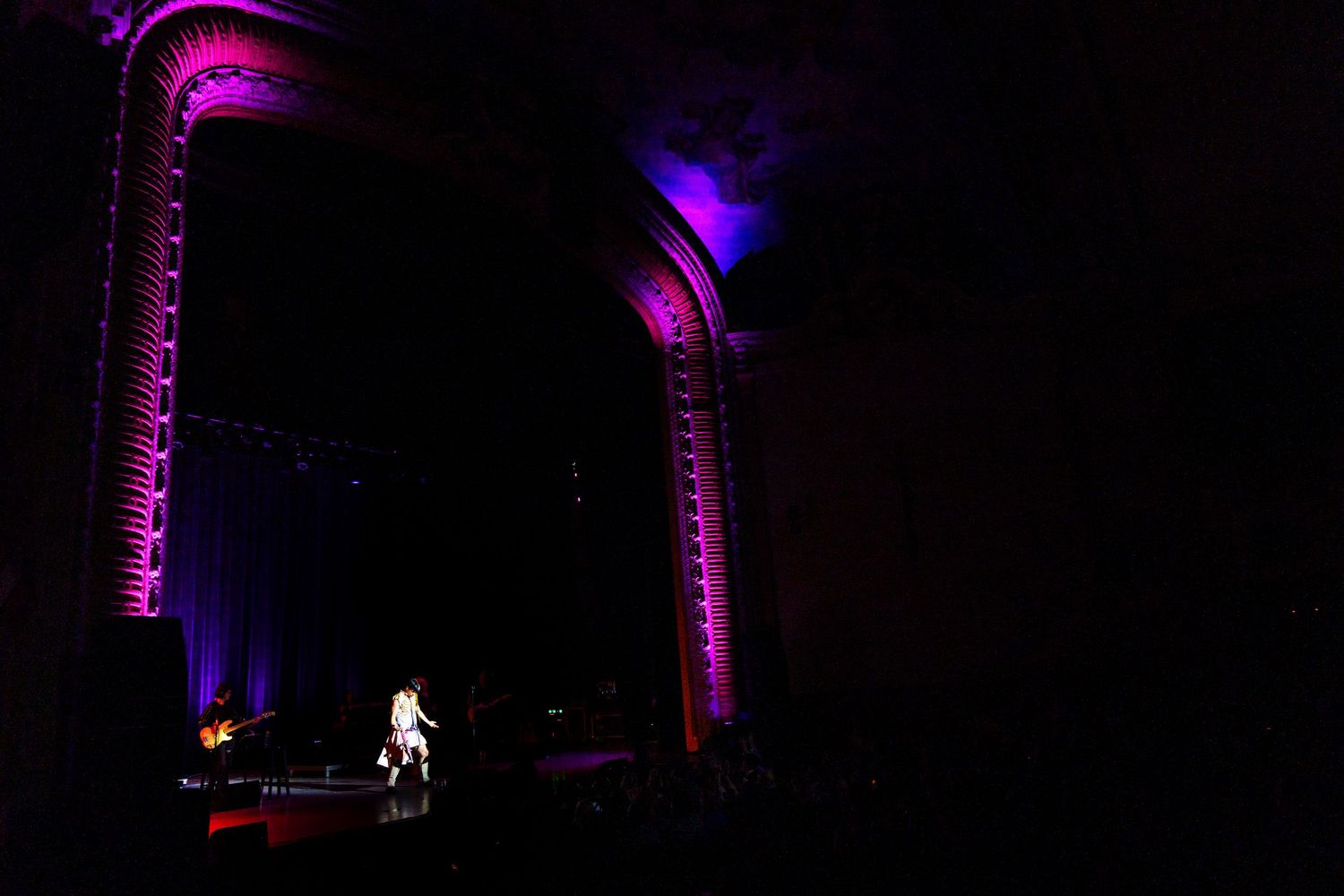 Theater stage illuminated in purple lighting during live performance.