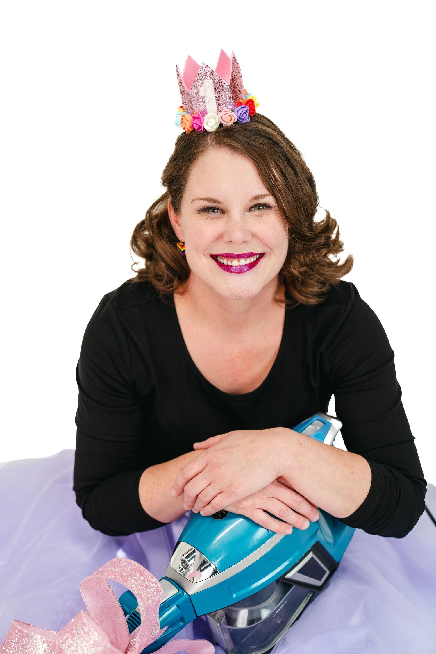 Whimsical studio portrait with sparkly crown and black top against white background.