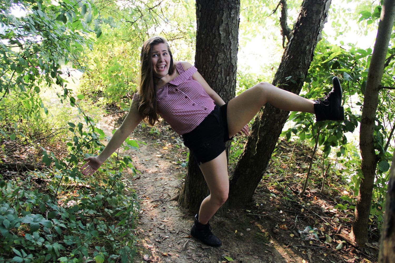 Person exploring a wooded trail among trees and foliage.