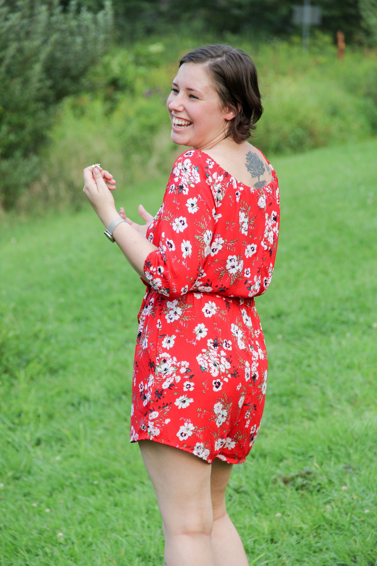 Casual outdoor photo in red floral romper against green grass.