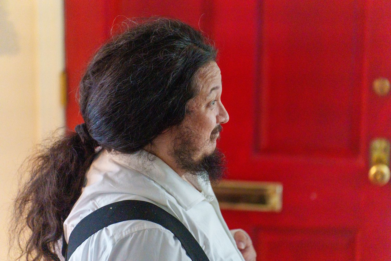 A side profile view against a vibrant red door background.