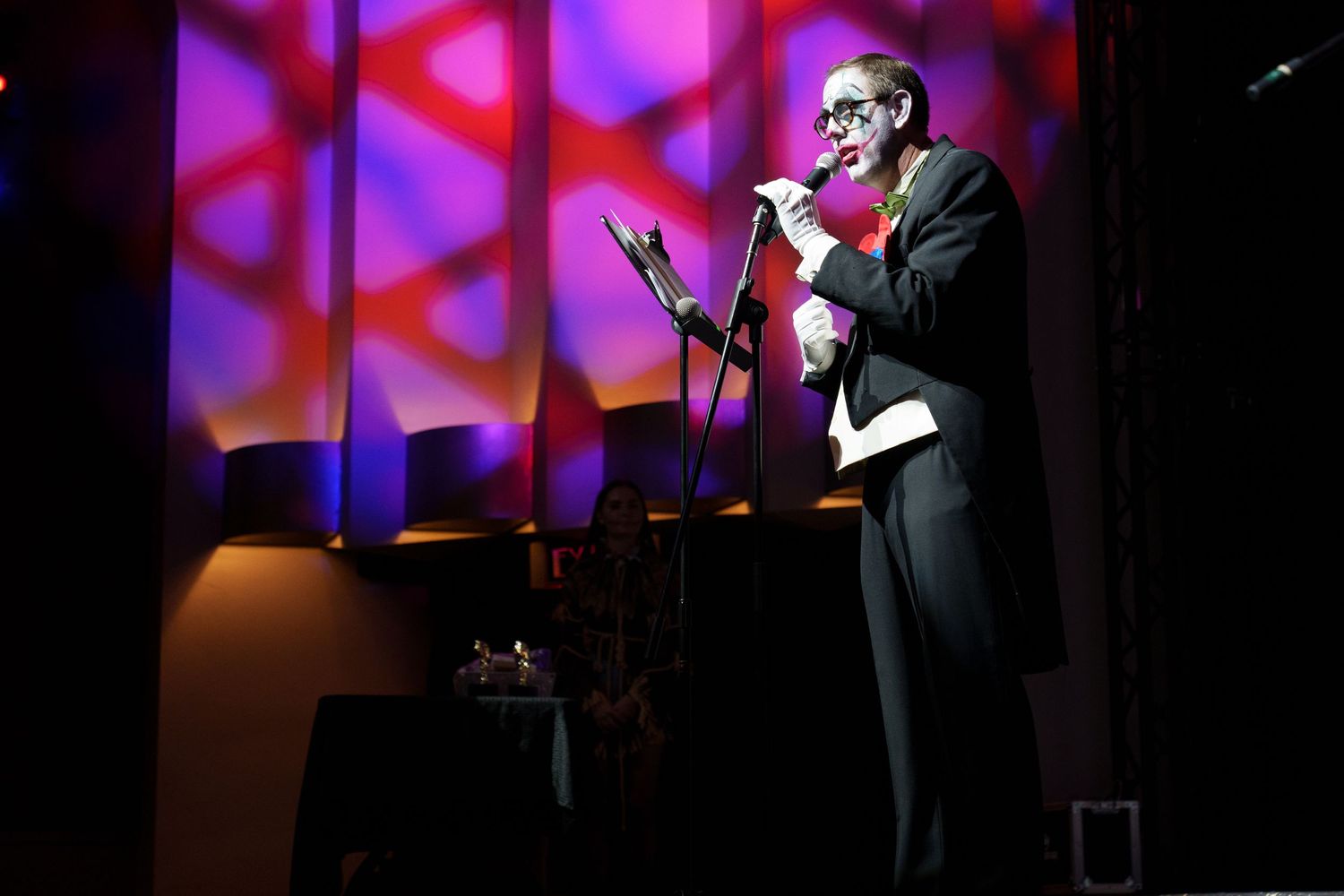 Performance on stage with pink and purple geometric lighting patterns.