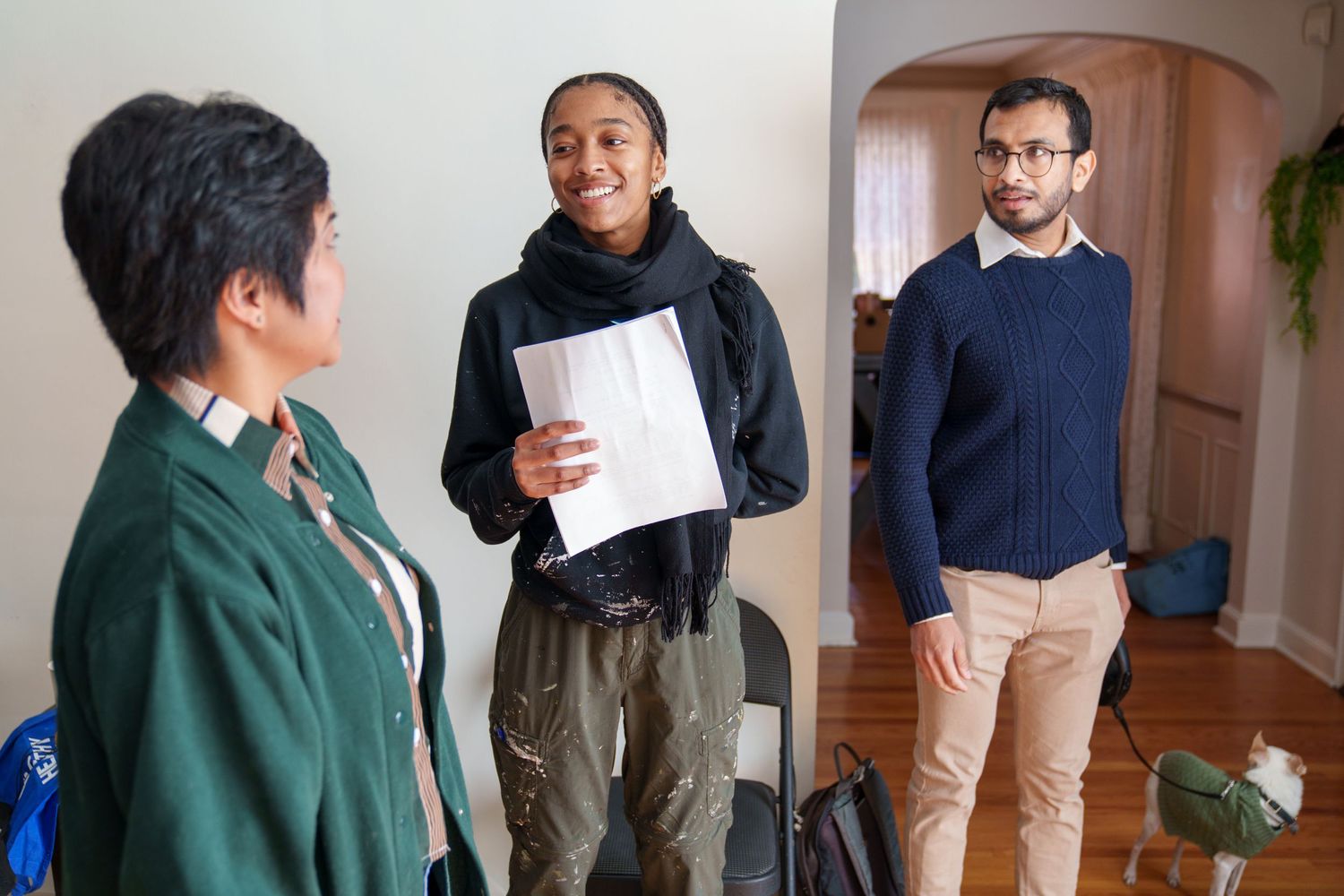 Group of people standing and interacting in a home interior setting.