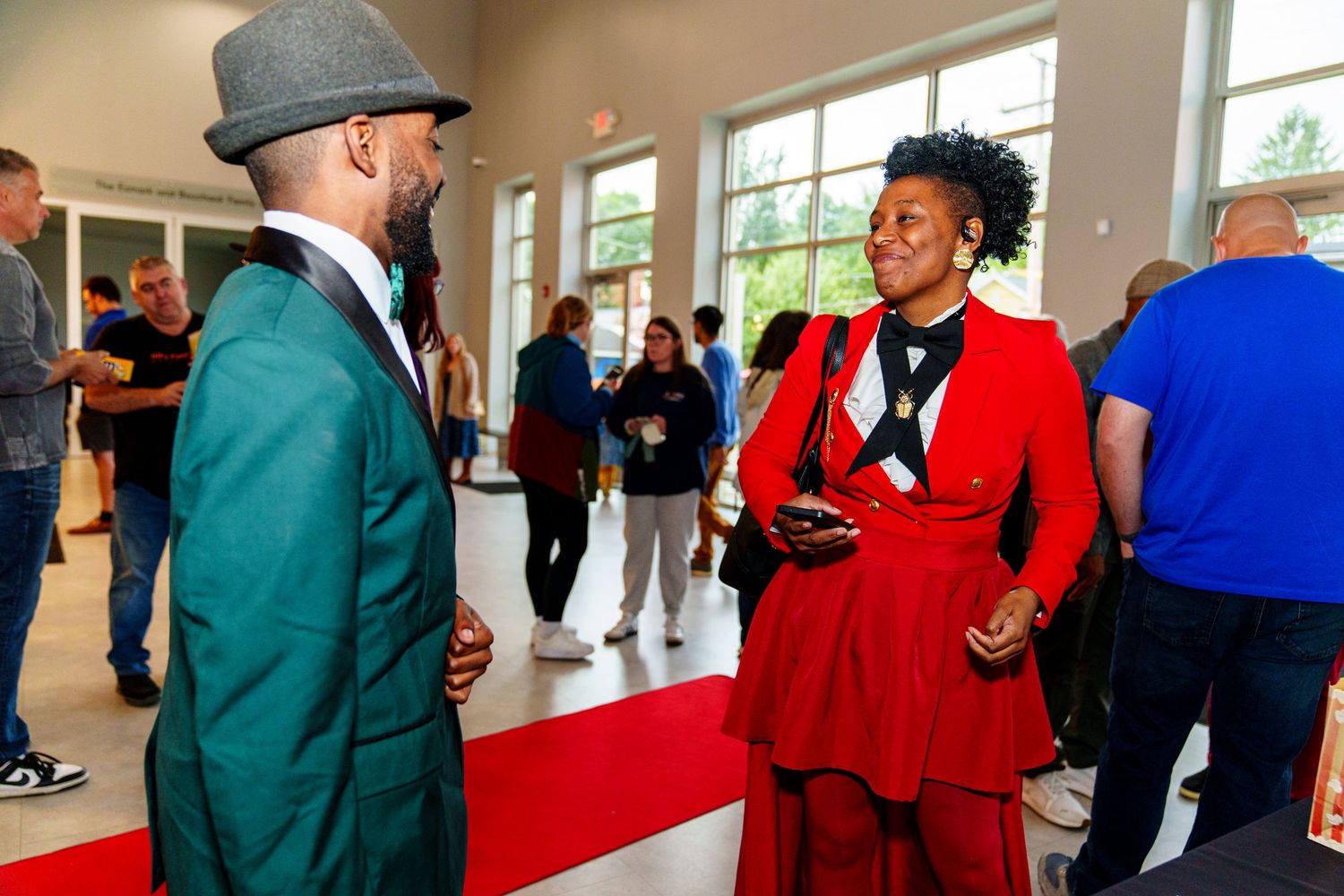 People in red and green jackets gathered together in a bright indoor space for a professional event.