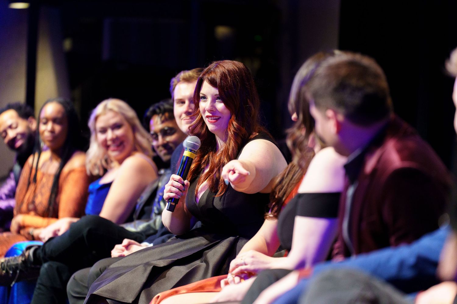 Audience members participating in discussion during live event with stage lighting.