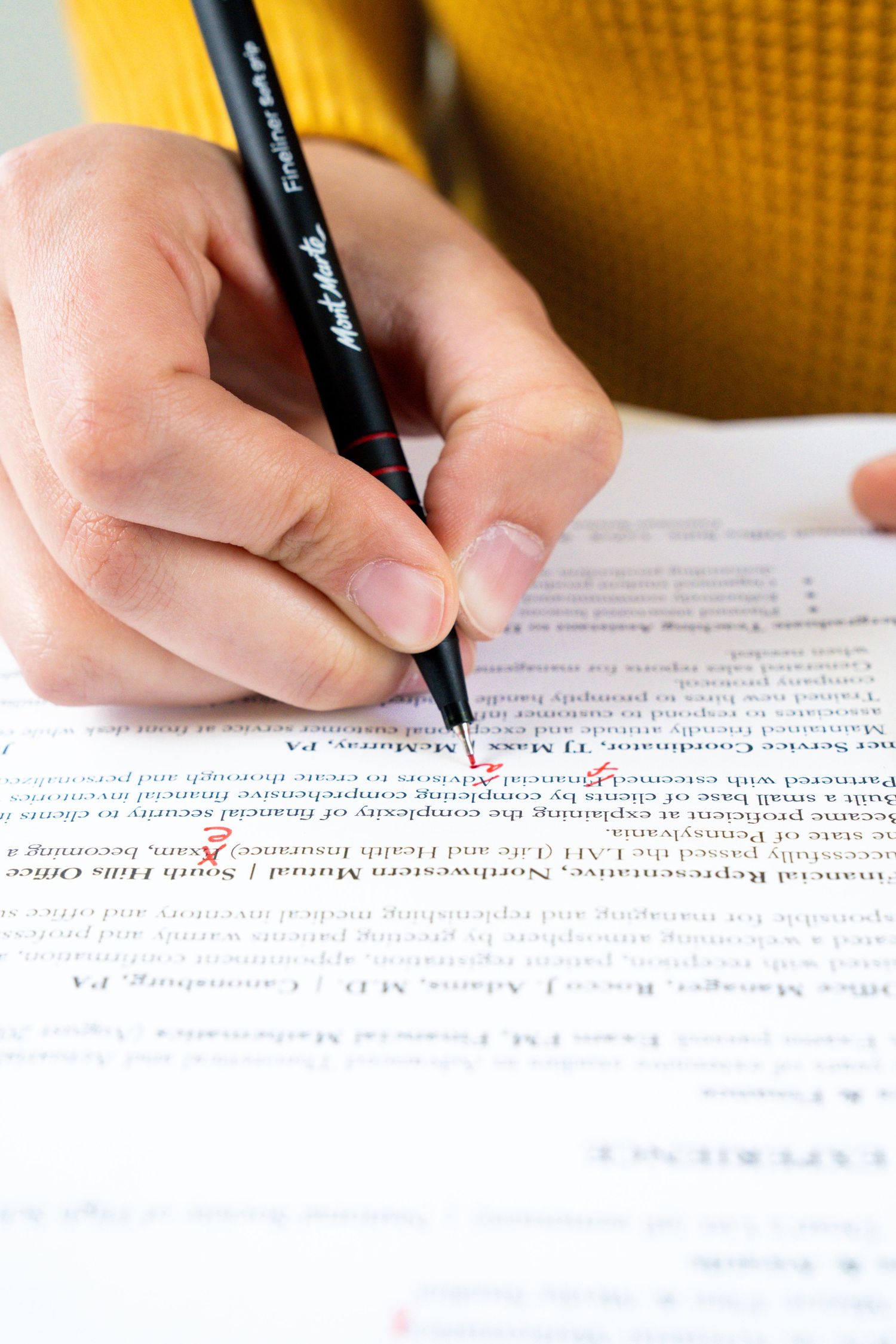 Close-up of hands marking text with pen on printed document.