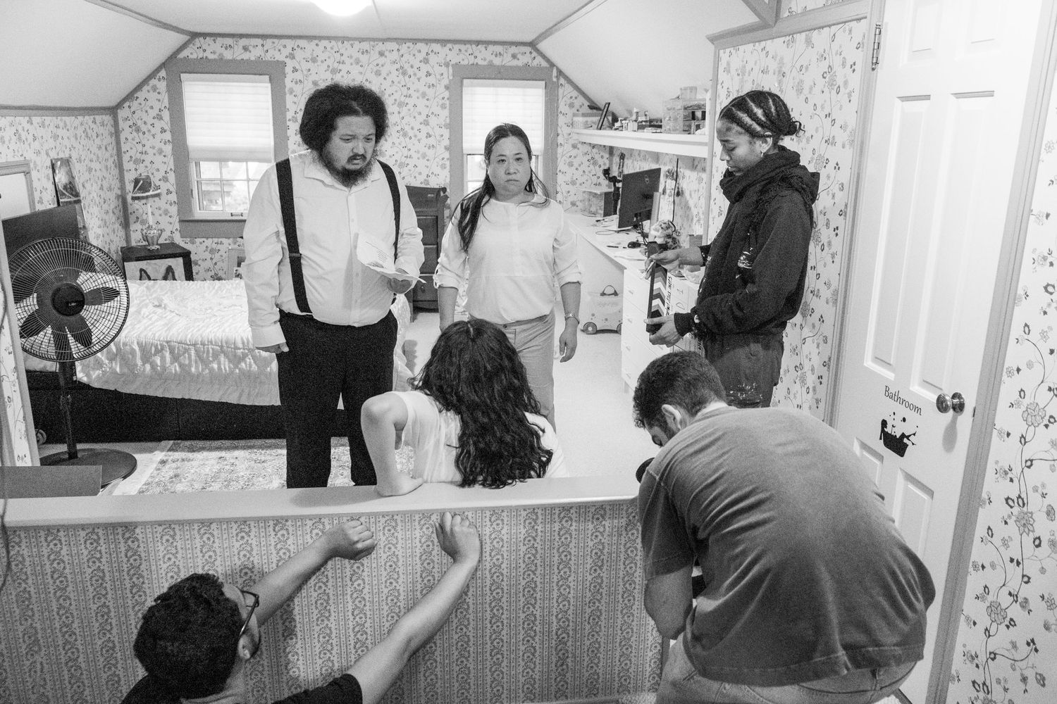 Behind the scenes footage of a film production in a wallpapered room.
