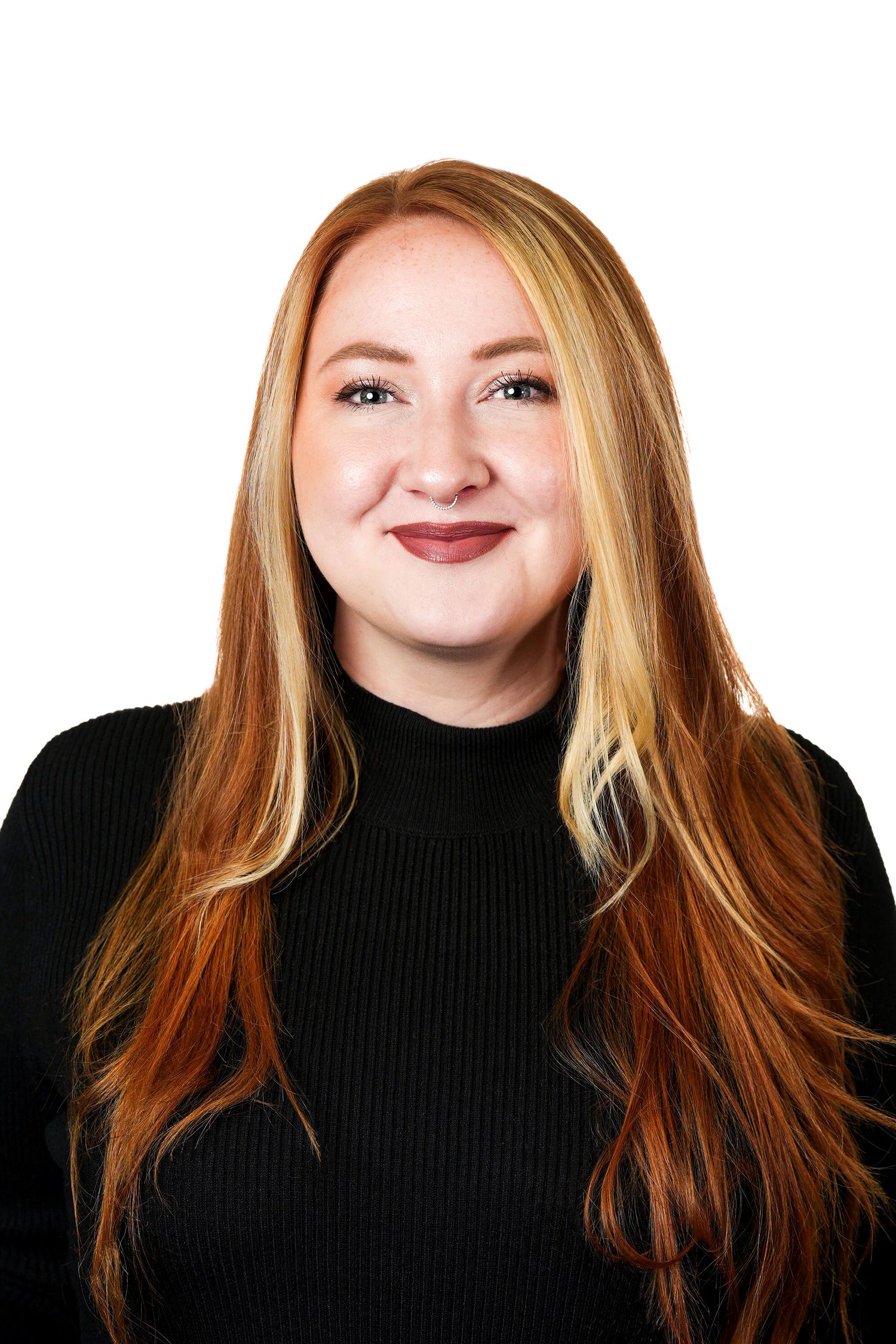 Professional headshot of someone wearing a black sweater with strawberry blonde hair and warm smile.