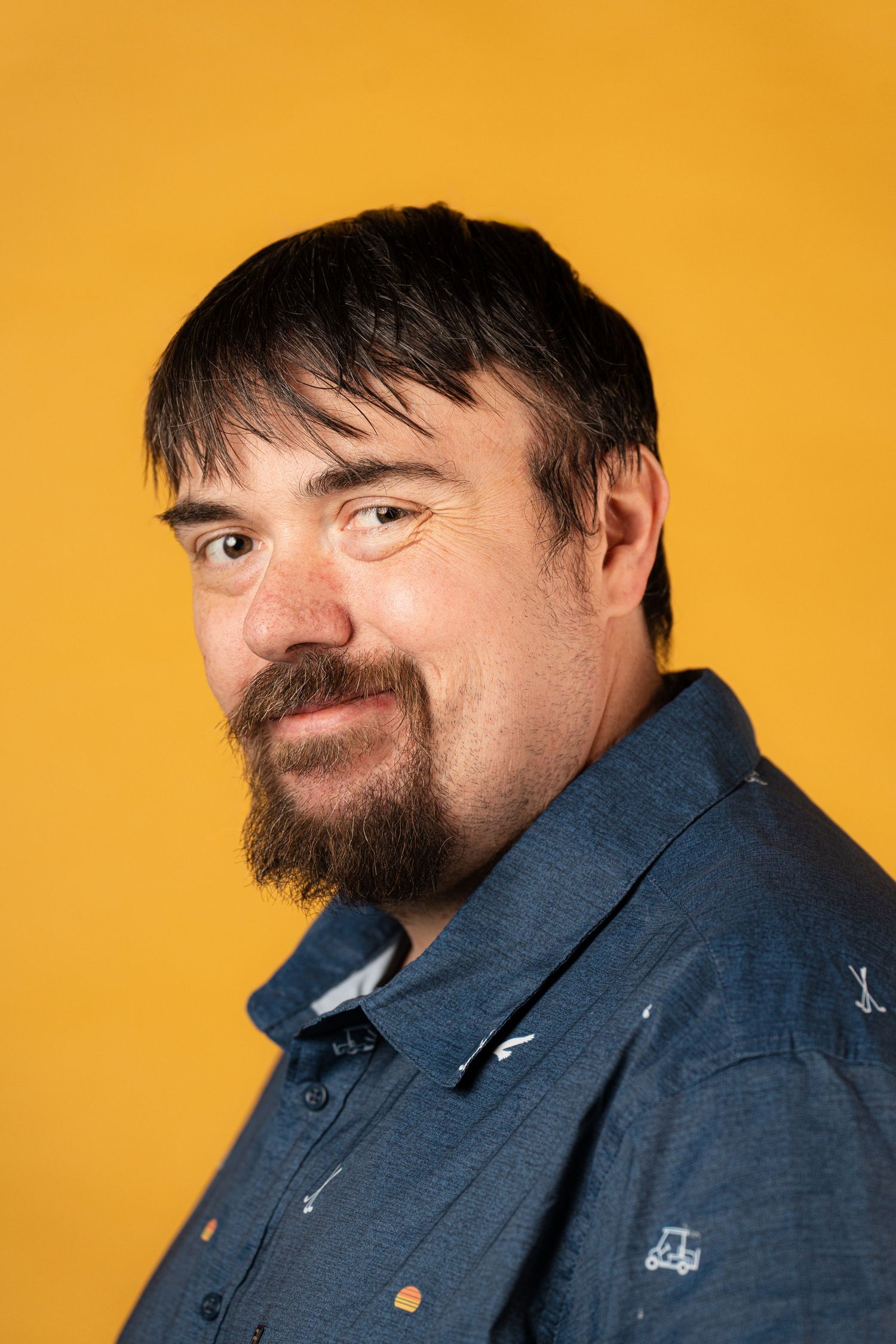 A series of headshots against an orange background showing a person in a blue denim shirt making different facial expressions.