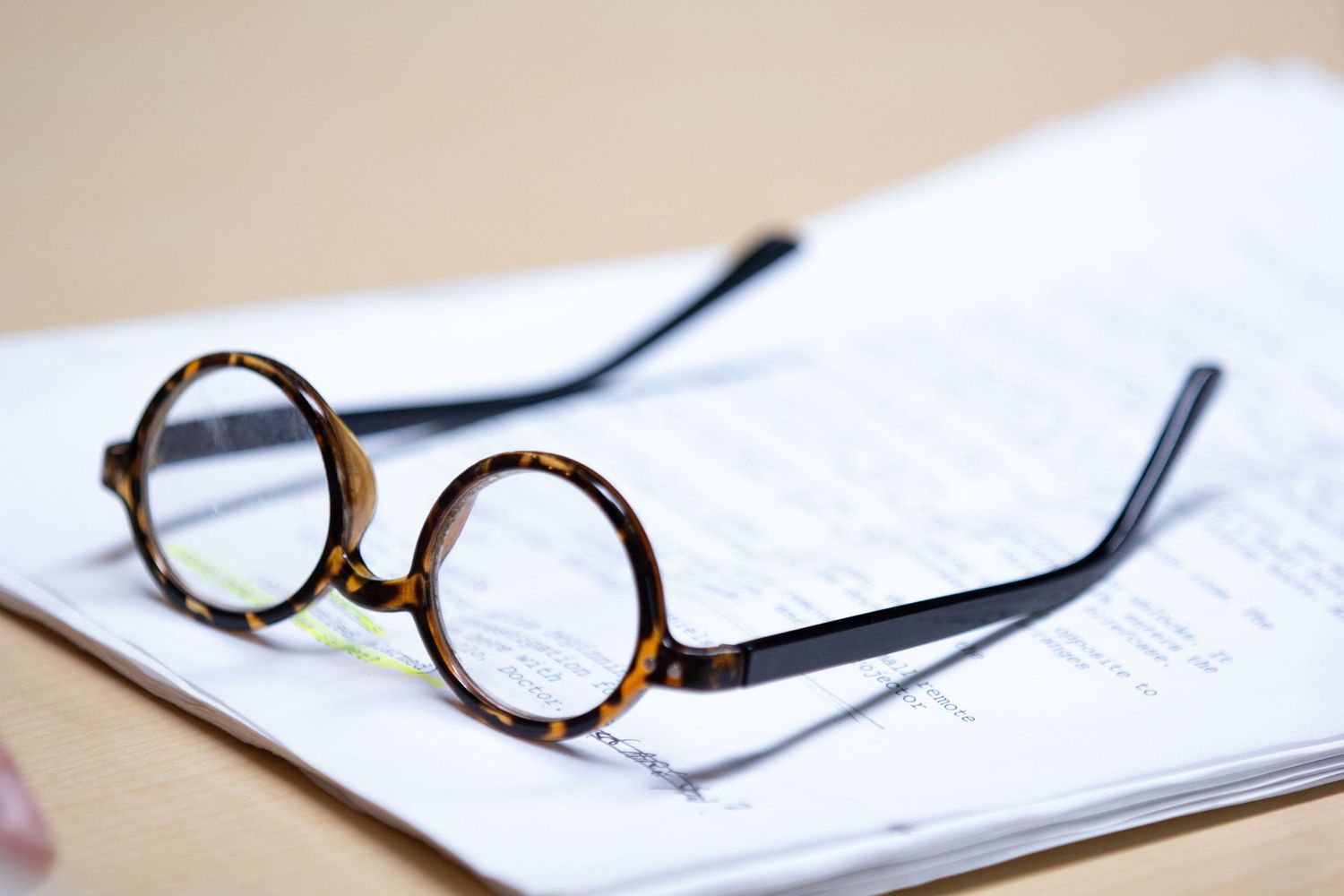 Vintage round reading glasses resting on open book pages.