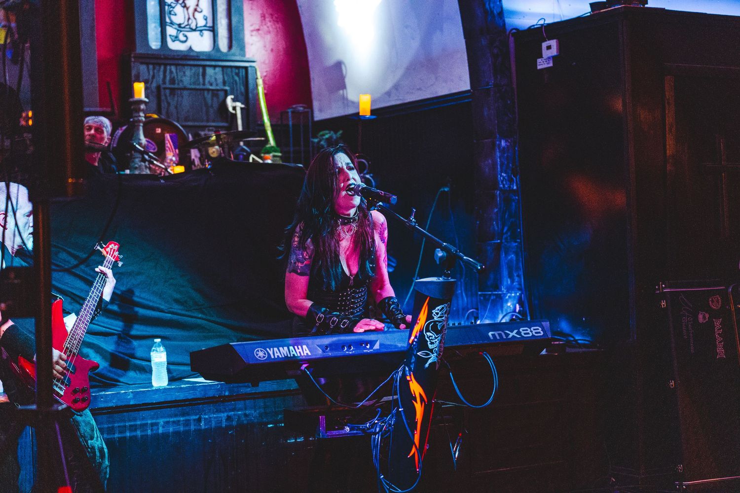 Colorful stage lighting illuminates a dark theater performance with dramatic blue and pink hues.