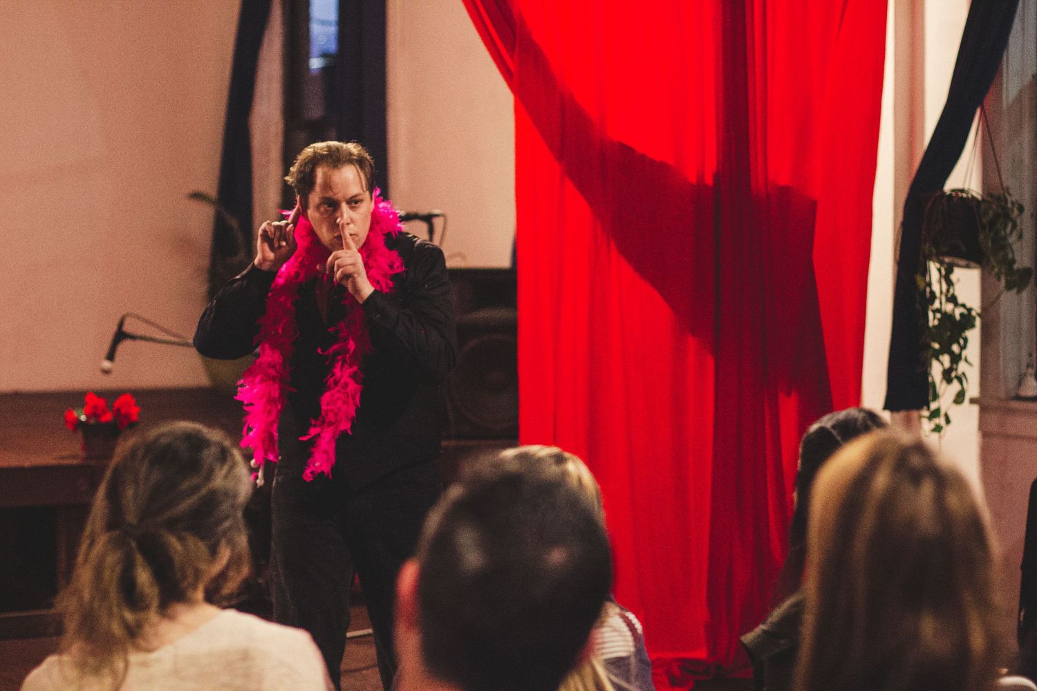Theater stage with bright red curtains and dramatic lighting during a performance.