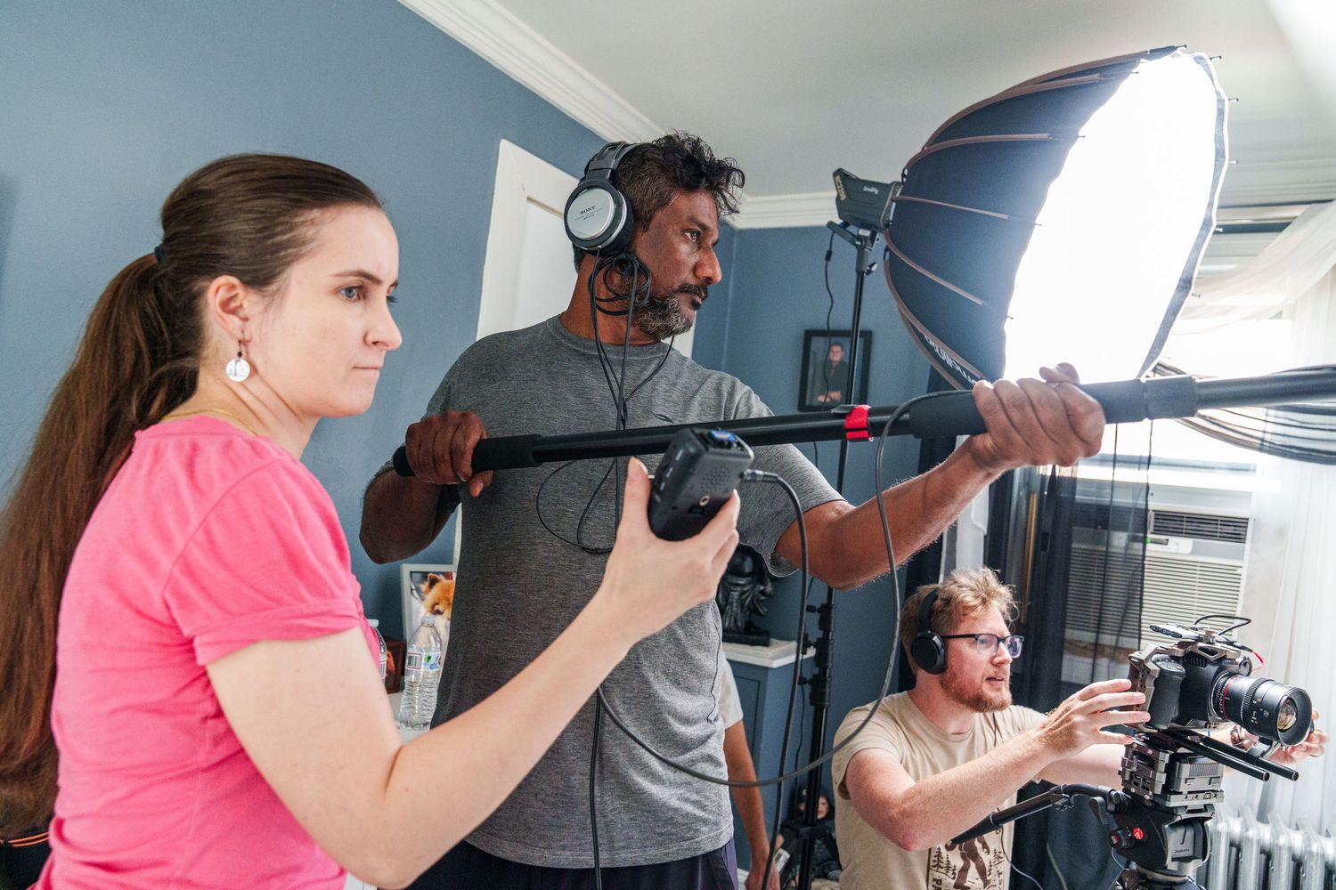 Film crew collaborating on set with camera, boom mic, and softbox lighting in an indoor studio.