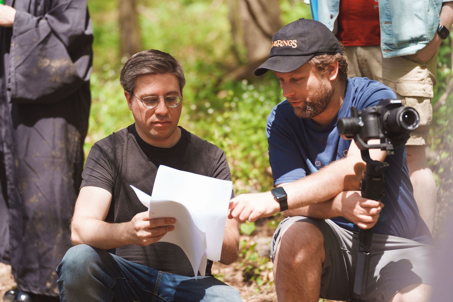 Film crew members reviewing scripts and equipment during an outdoor production.