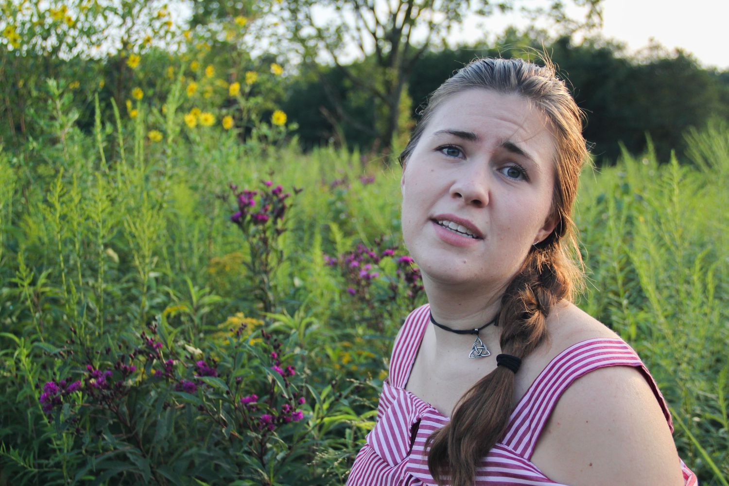Portrait in a wildflower meadow at sunset wearing pink striped top.