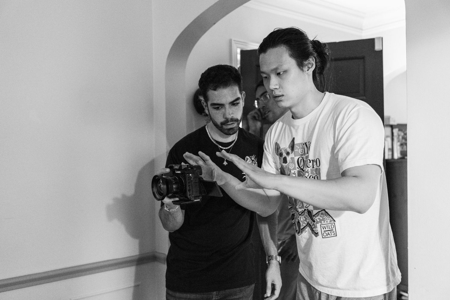 Film crew working together in a white-walled interior setting.