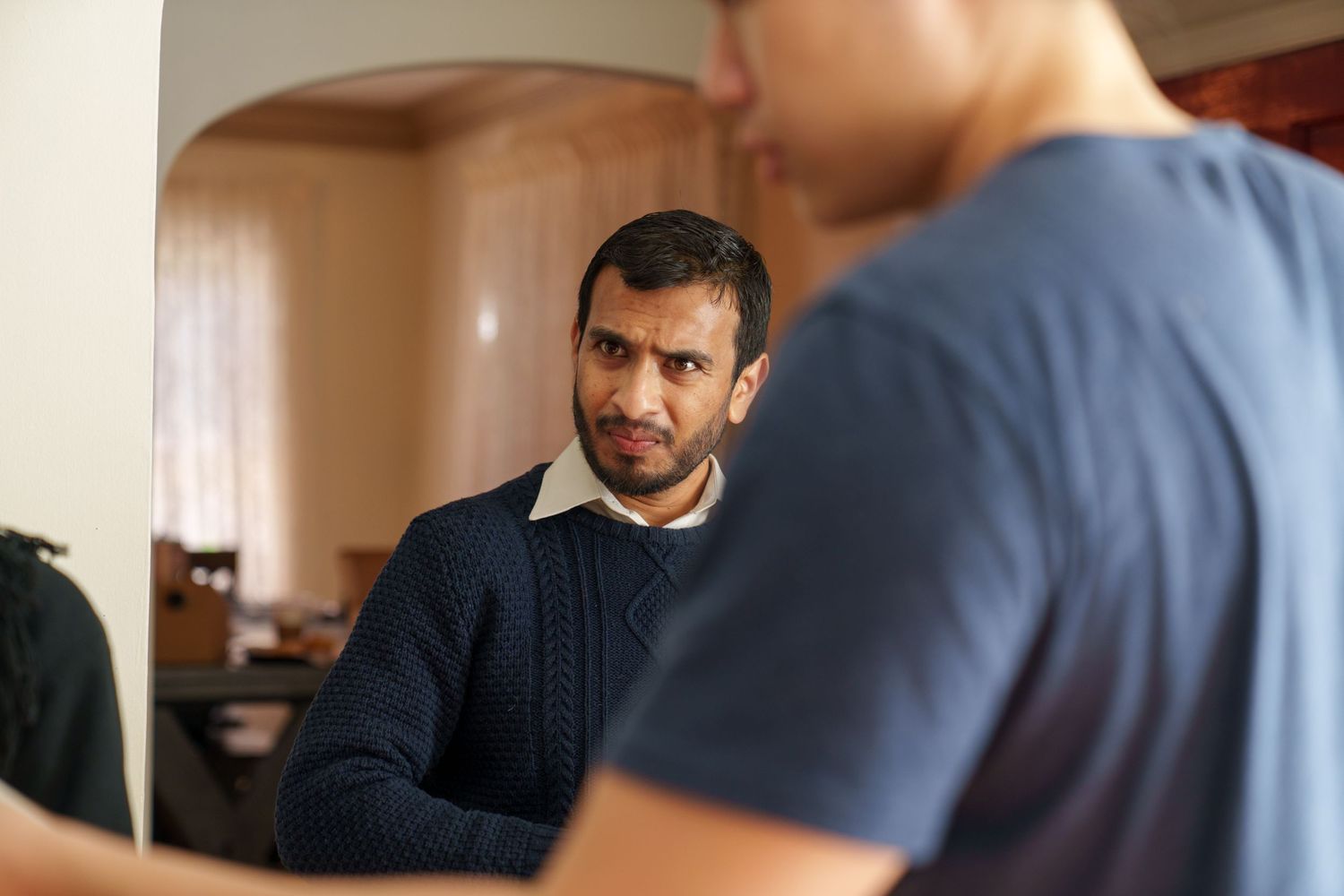 People having a conversation in an indoor setting with natural lighting.