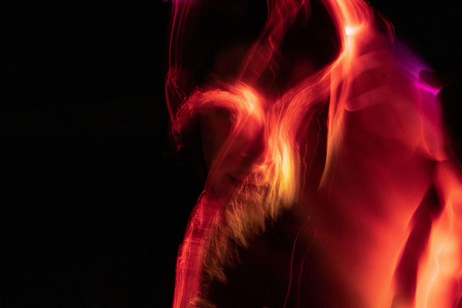 Glowing red and pink light streams form dynamic abstract patterns.