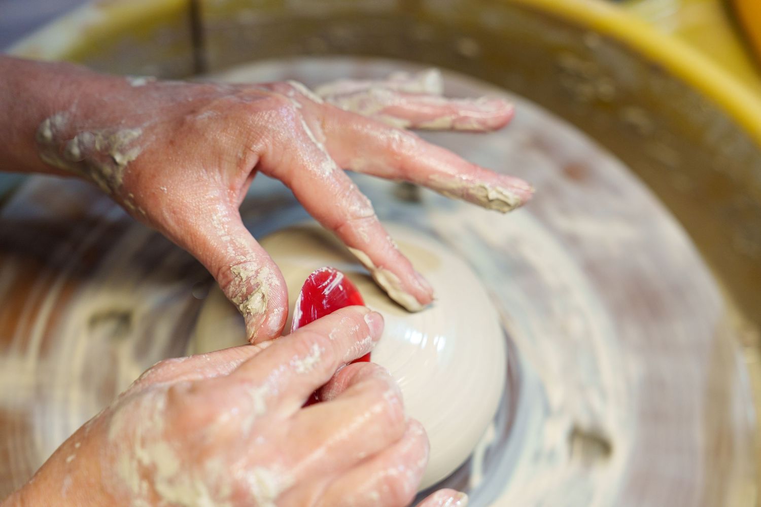 Hands kneading and shaping raw dough on a floured wooden surface in a sequence of preparation steps.