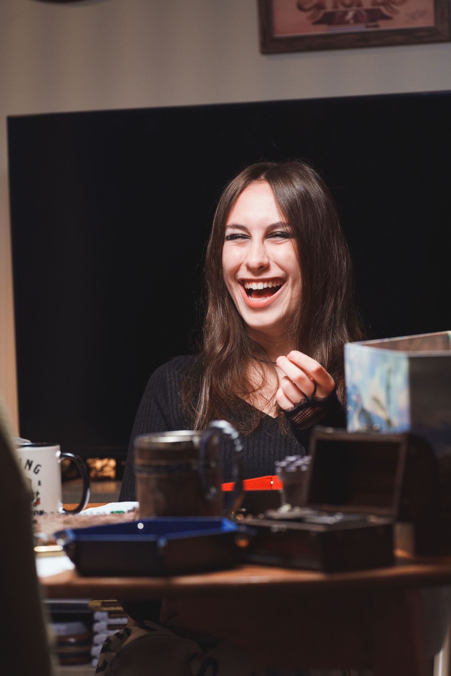 Person smiles while engaged in tabletop gaming with miniatures and props.