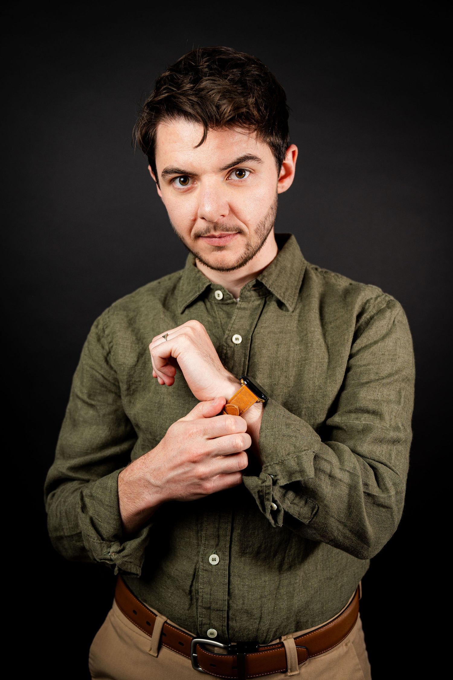 A person in an olive shirt eats a snack in a sequence of dramatic poses against a black backdrop.