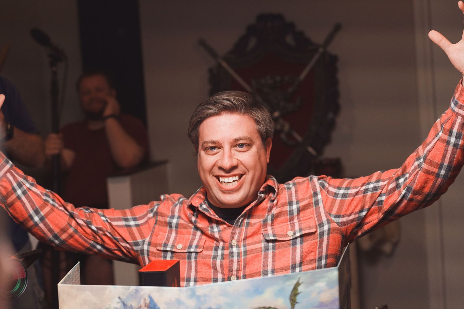 Person in orange plaid shirt raises arms in celebration with joyful expression.