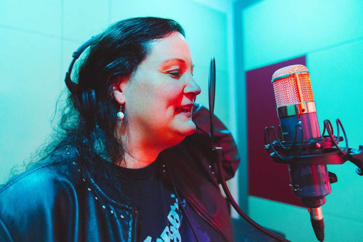 Professional recording session with condenser microphone in blue-lit studio.