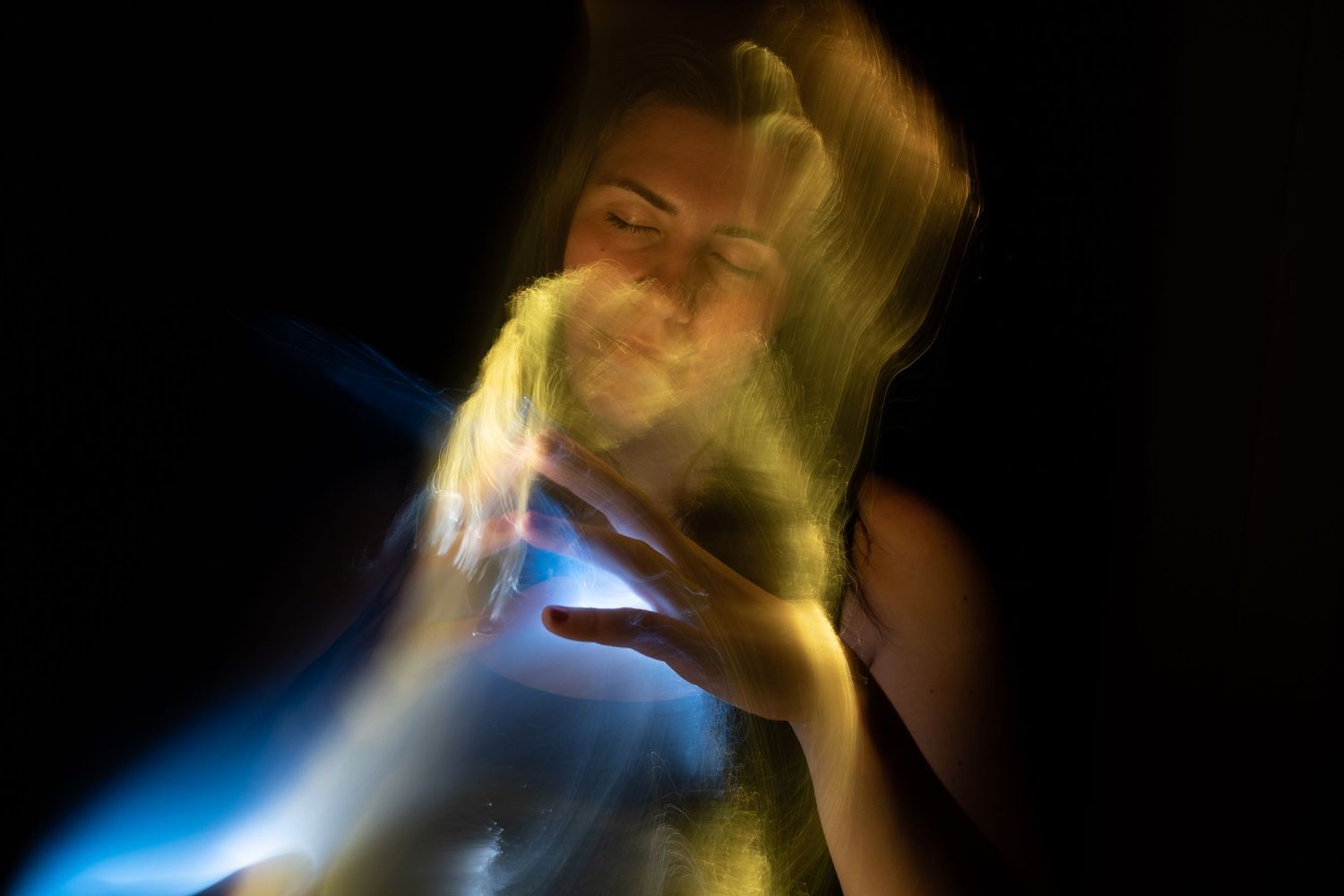 Experimental photography with yellow and blue light trails creating dreamy motion effects.