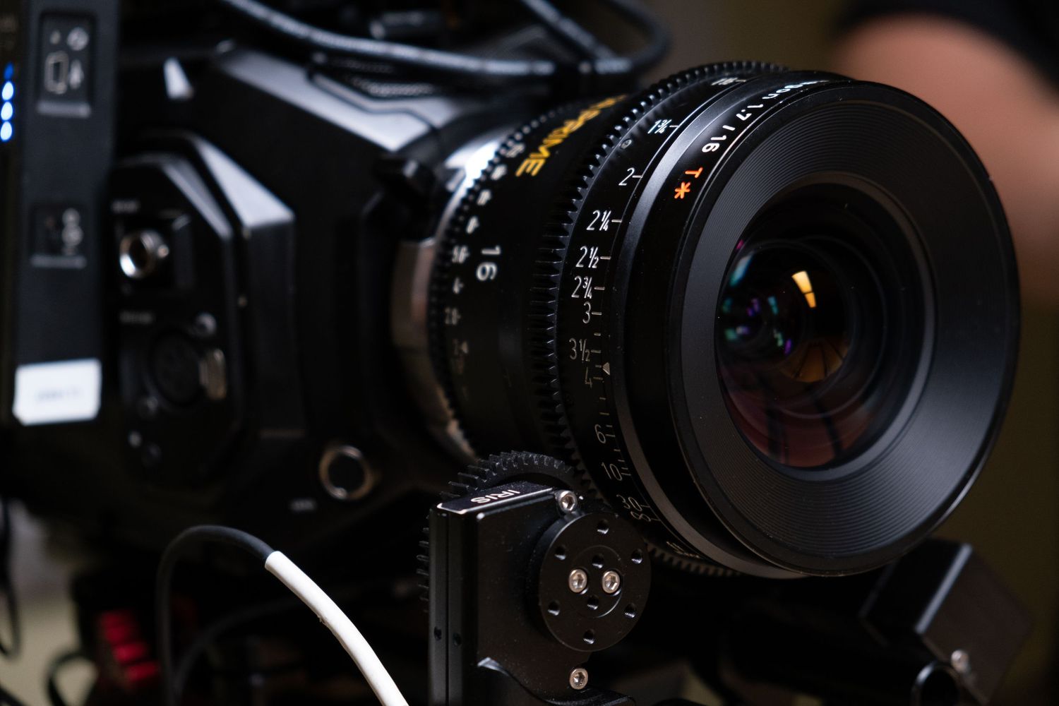 Close-up of a professional cinema camera lens with detailed focus markings in low light.