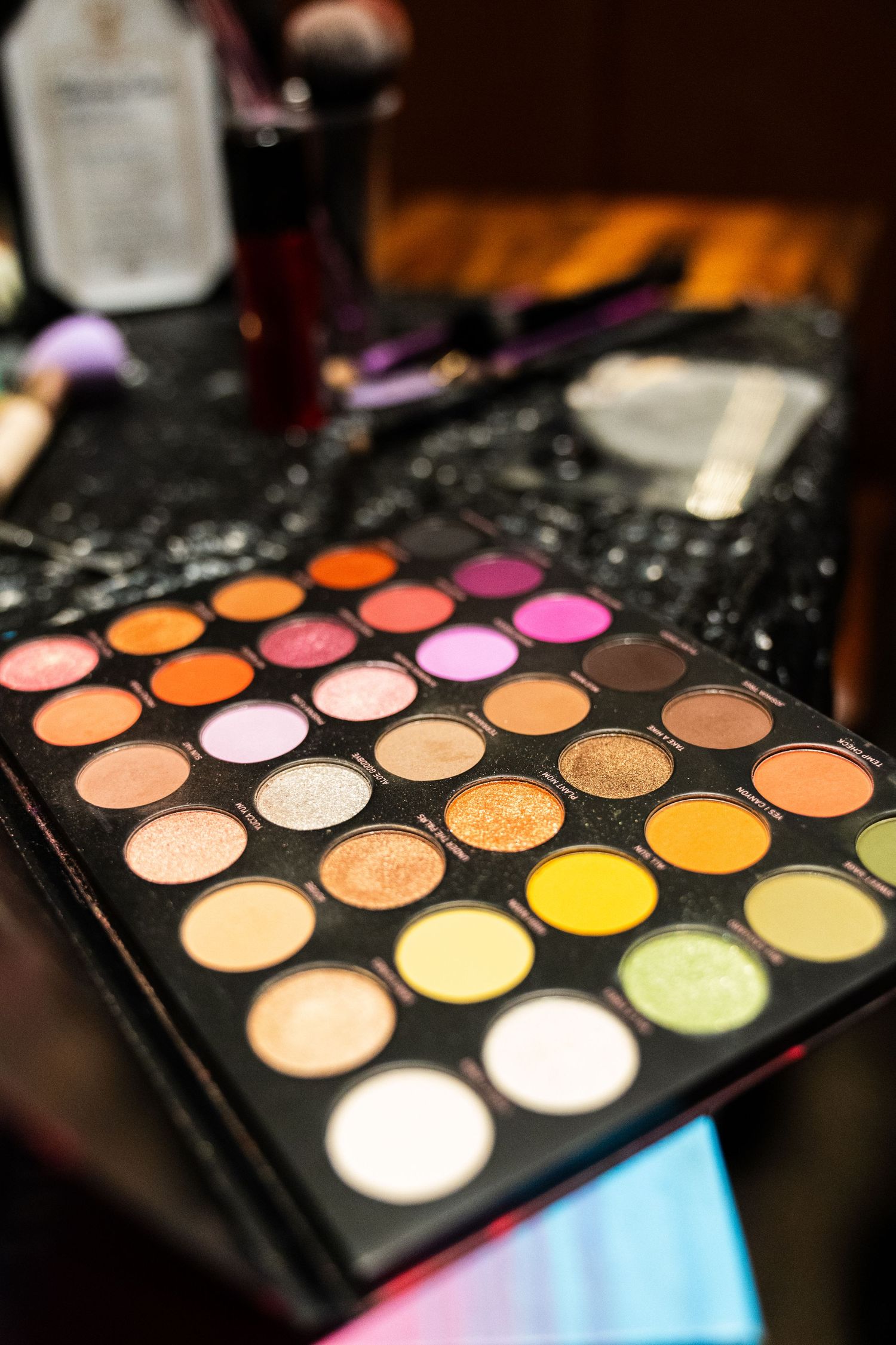 Colorful eyeshadow palette with vibrant shades on a dark makeup table.