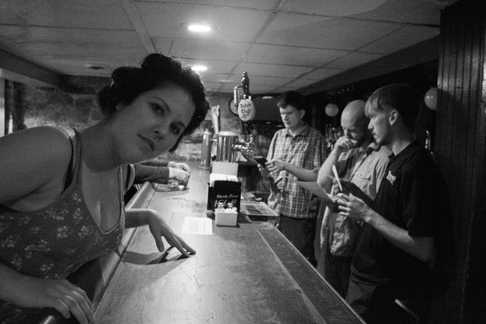 People socializing at a bar counter in black and white photo.
