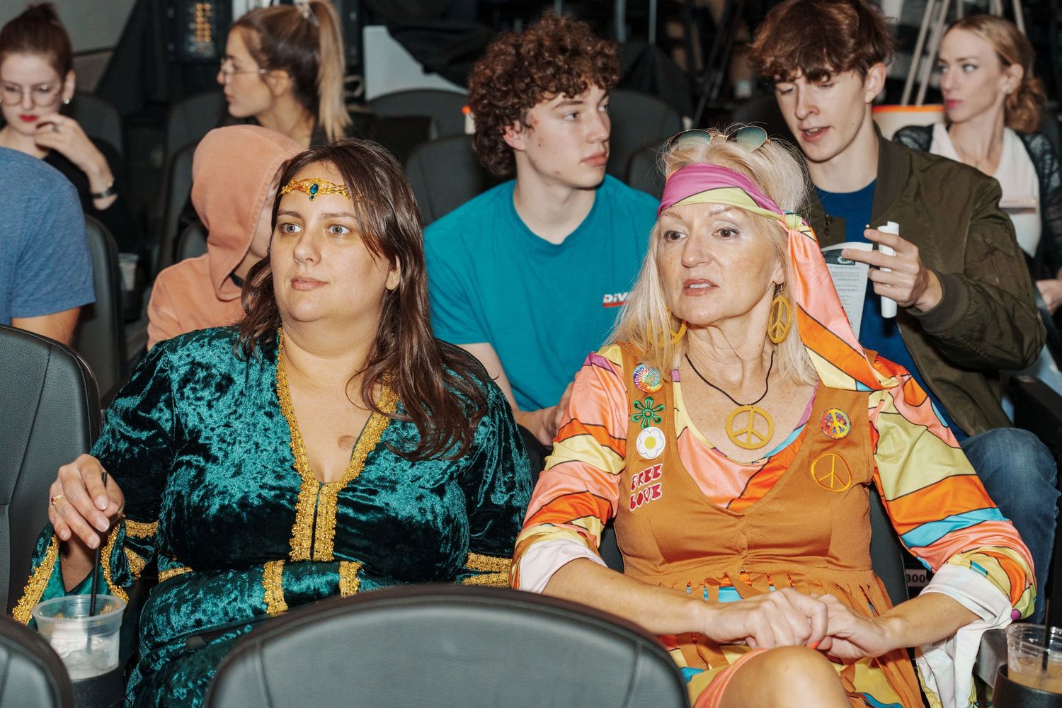 Event attendees in colorful attire engaged in conversation at indoor gathering.