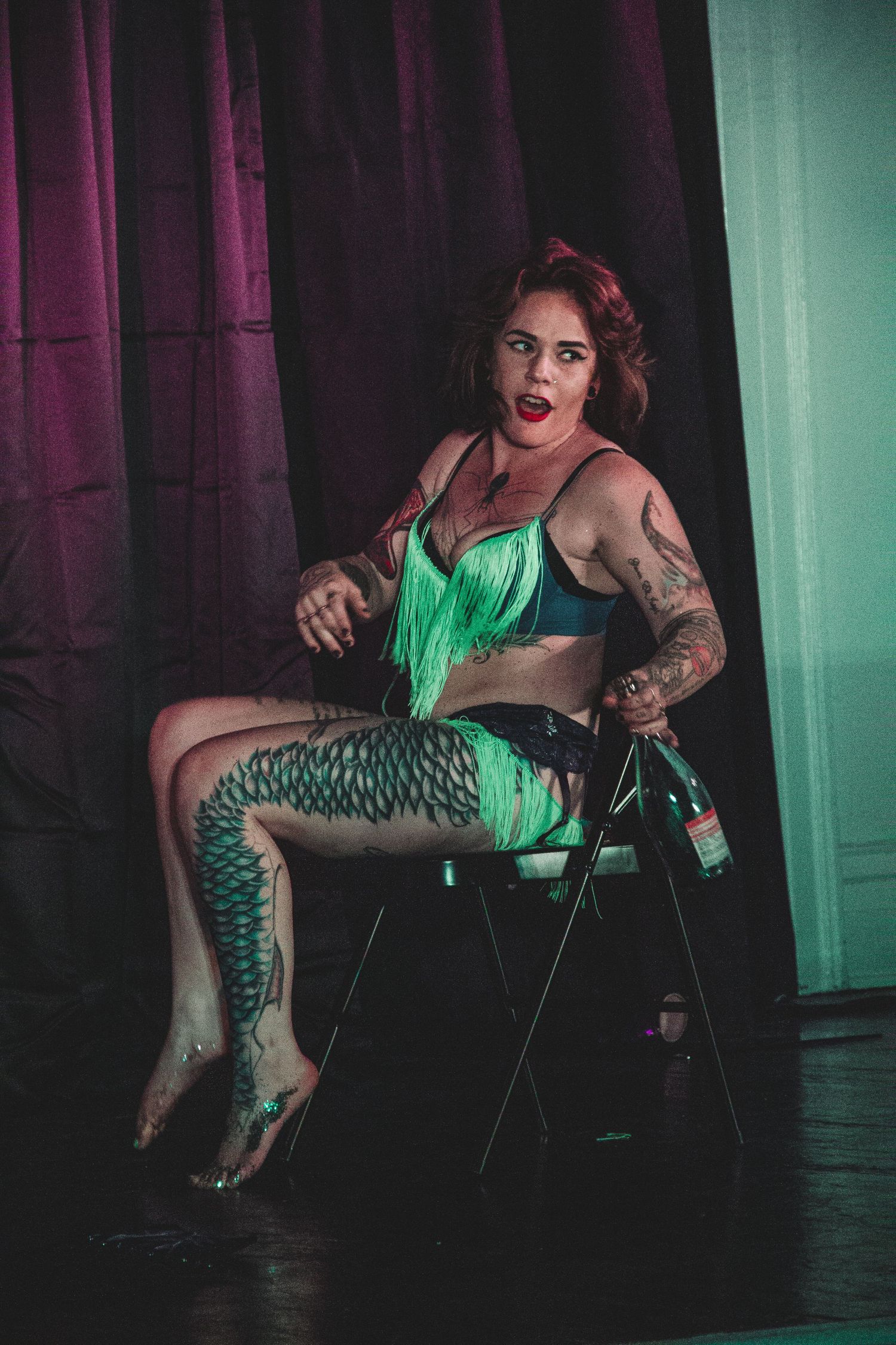 A dance performance featuring patterned leggings and mint green costume elements on a dimly lit stage.