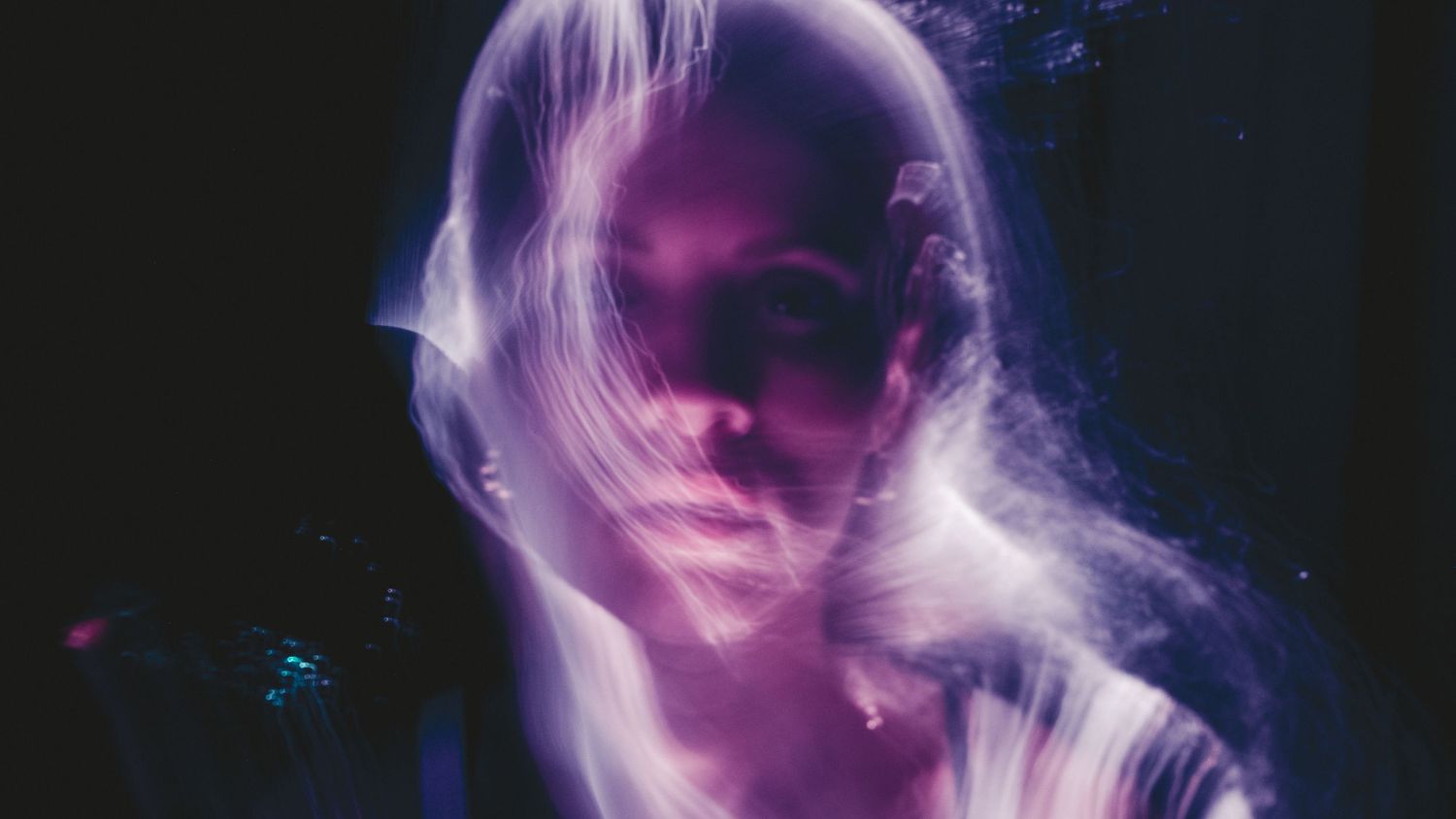 Abstract purple light trails create ethereal patterns against a dark background.